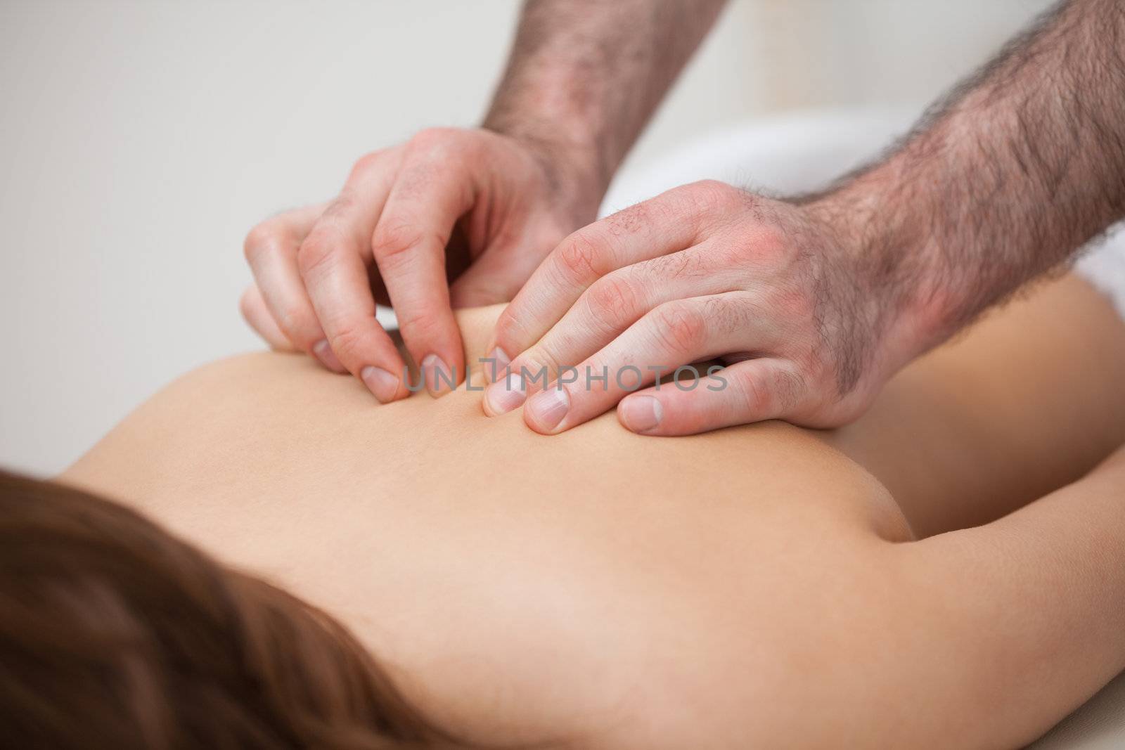 Chiropractor massaging his patient while using his fingertips in a room