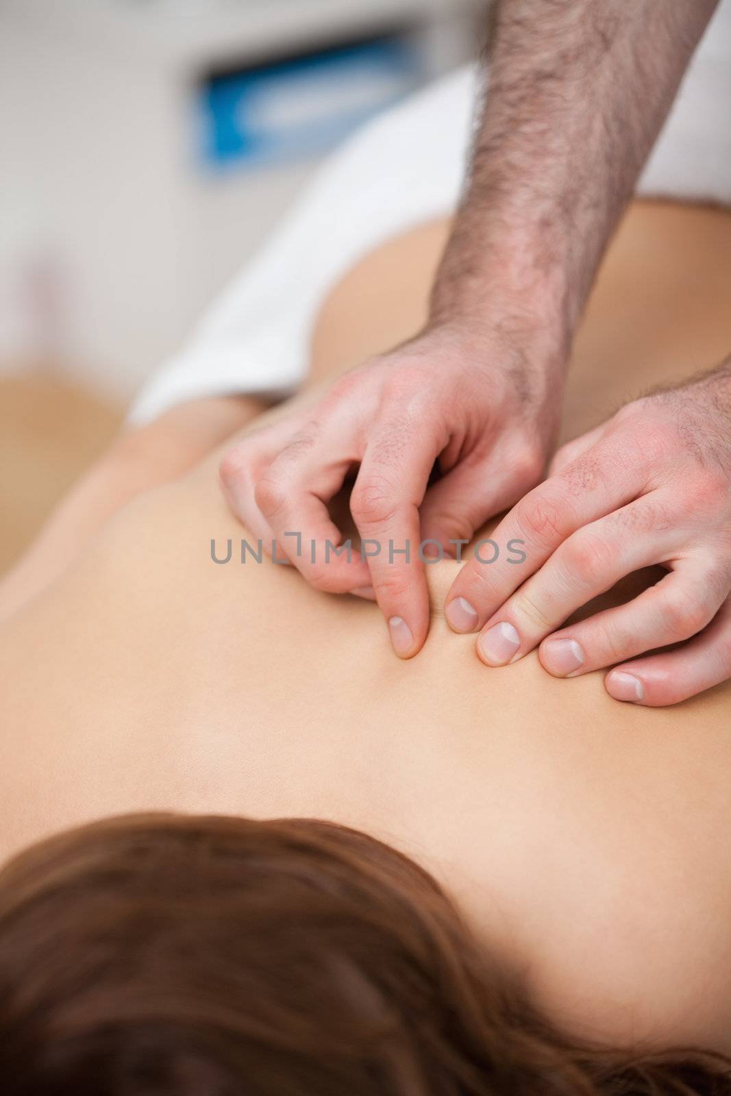 Back of a woman being massaging while fingertips of doctor in a room
