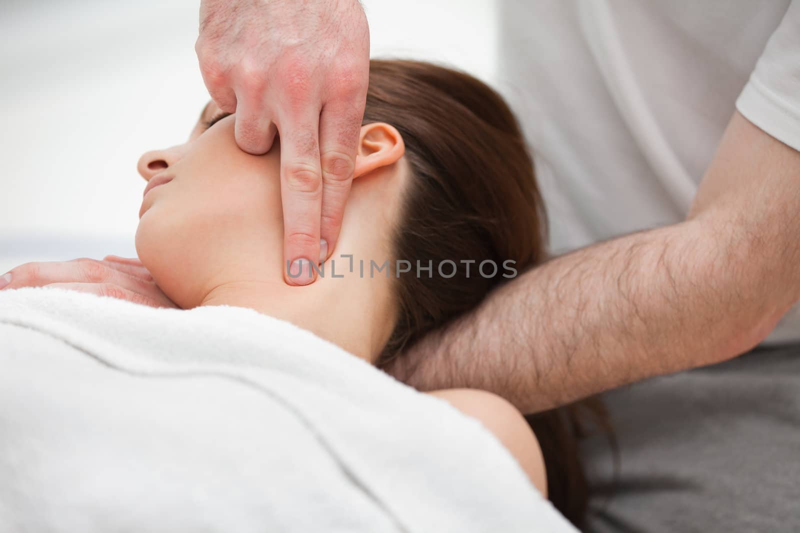 Doctor manipulating the neck of a woman while using his fingertips indoors