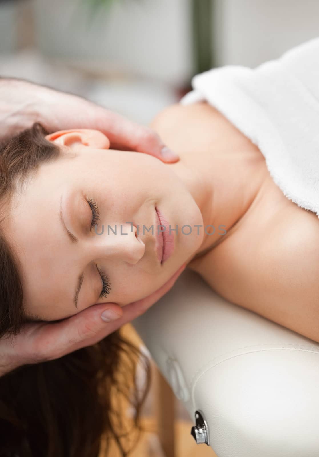 Peaceful woman being massaging on the neck by a therapist in a room