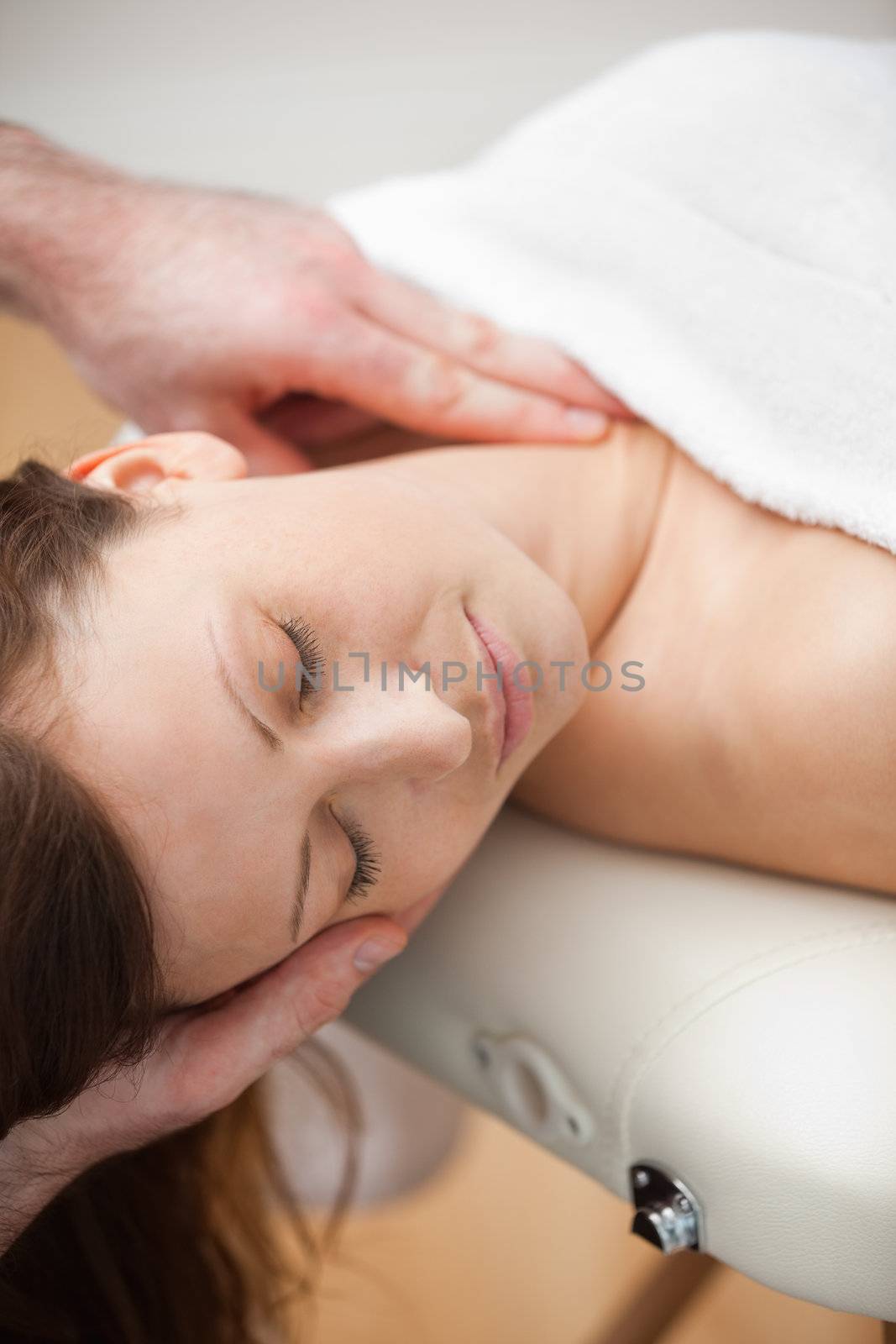 Neck of a patient being massaged by a chiropractor in a room