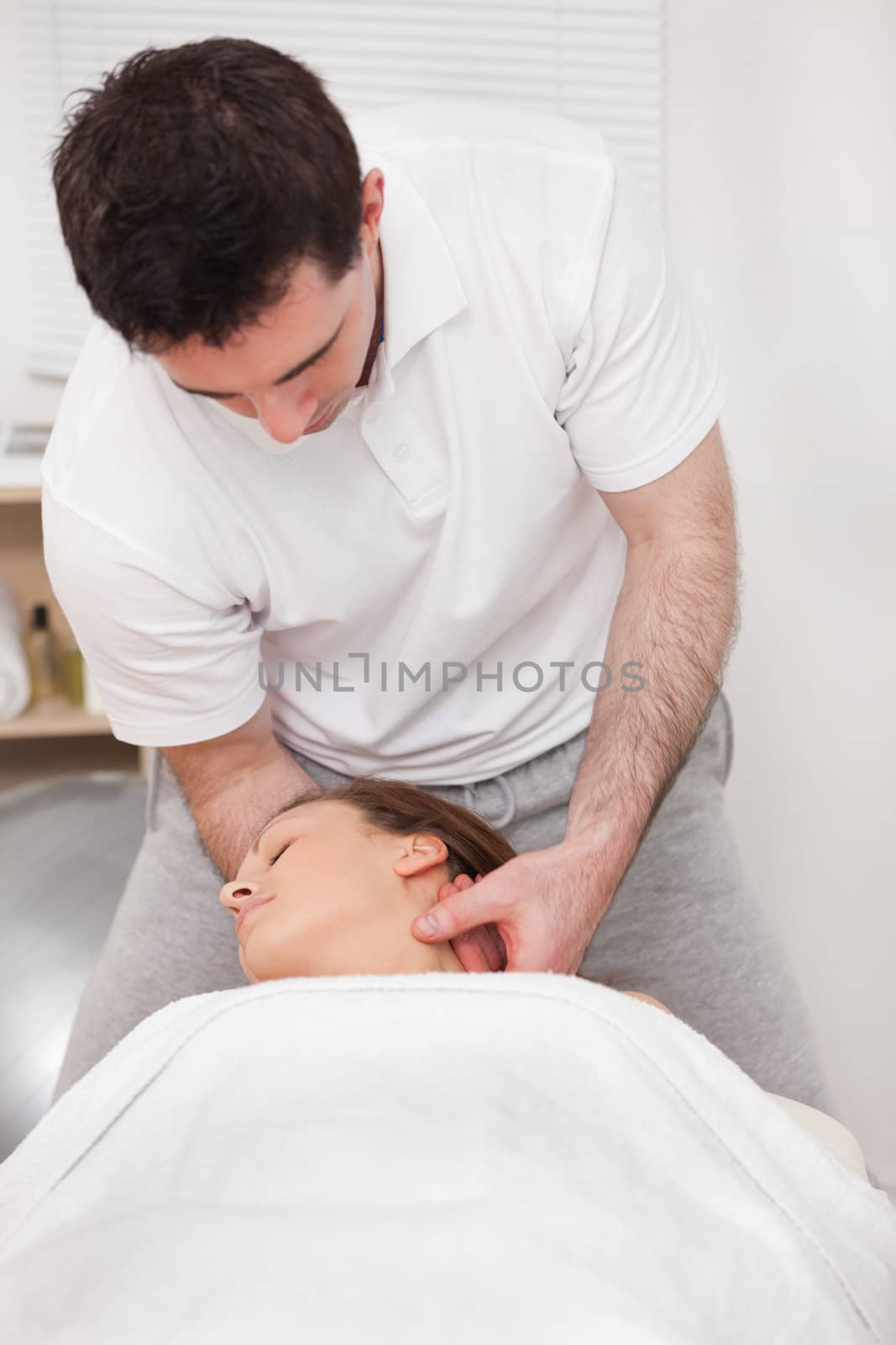 Therapist manipulating the neck of his patient while standing in a room