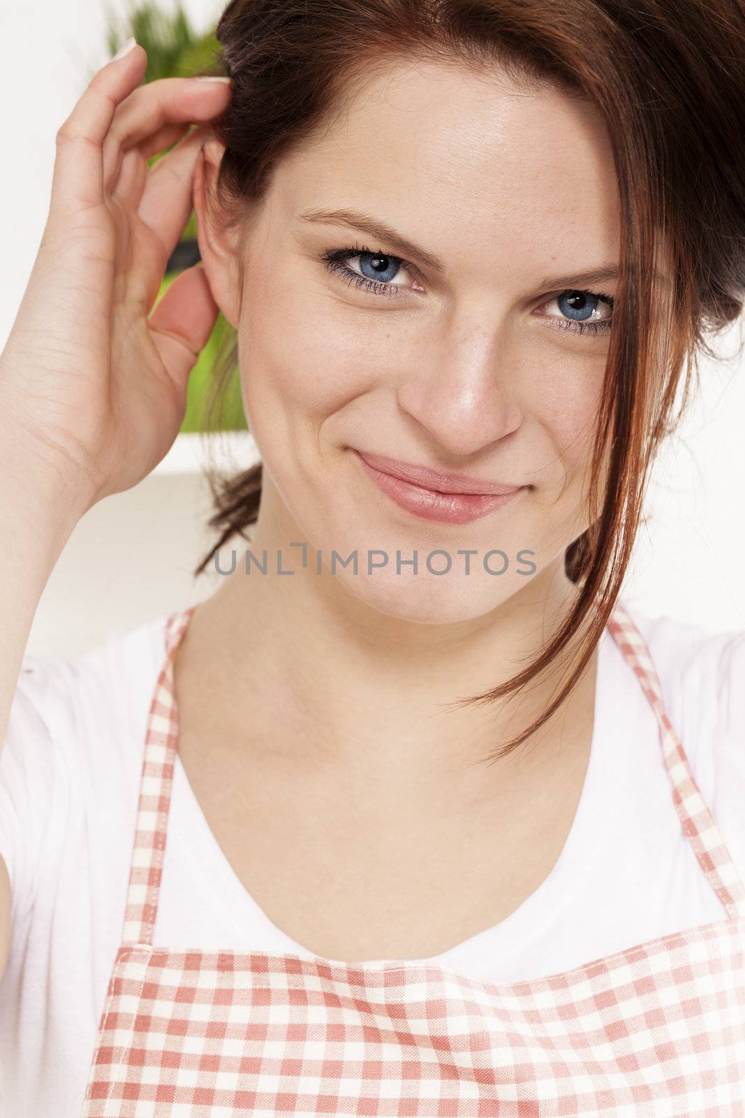 portrait of a young woman wearing a apron  in her kitchen