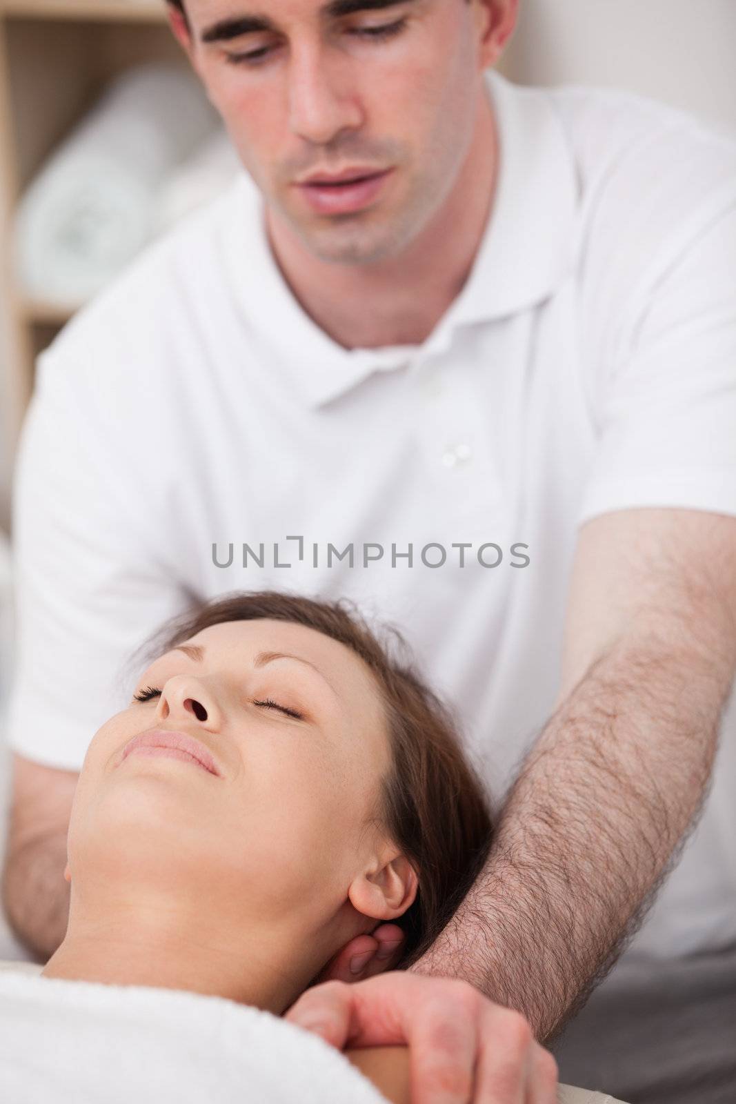 Physiotherapist manipulating the neck of his patient by Wavebreakmedia