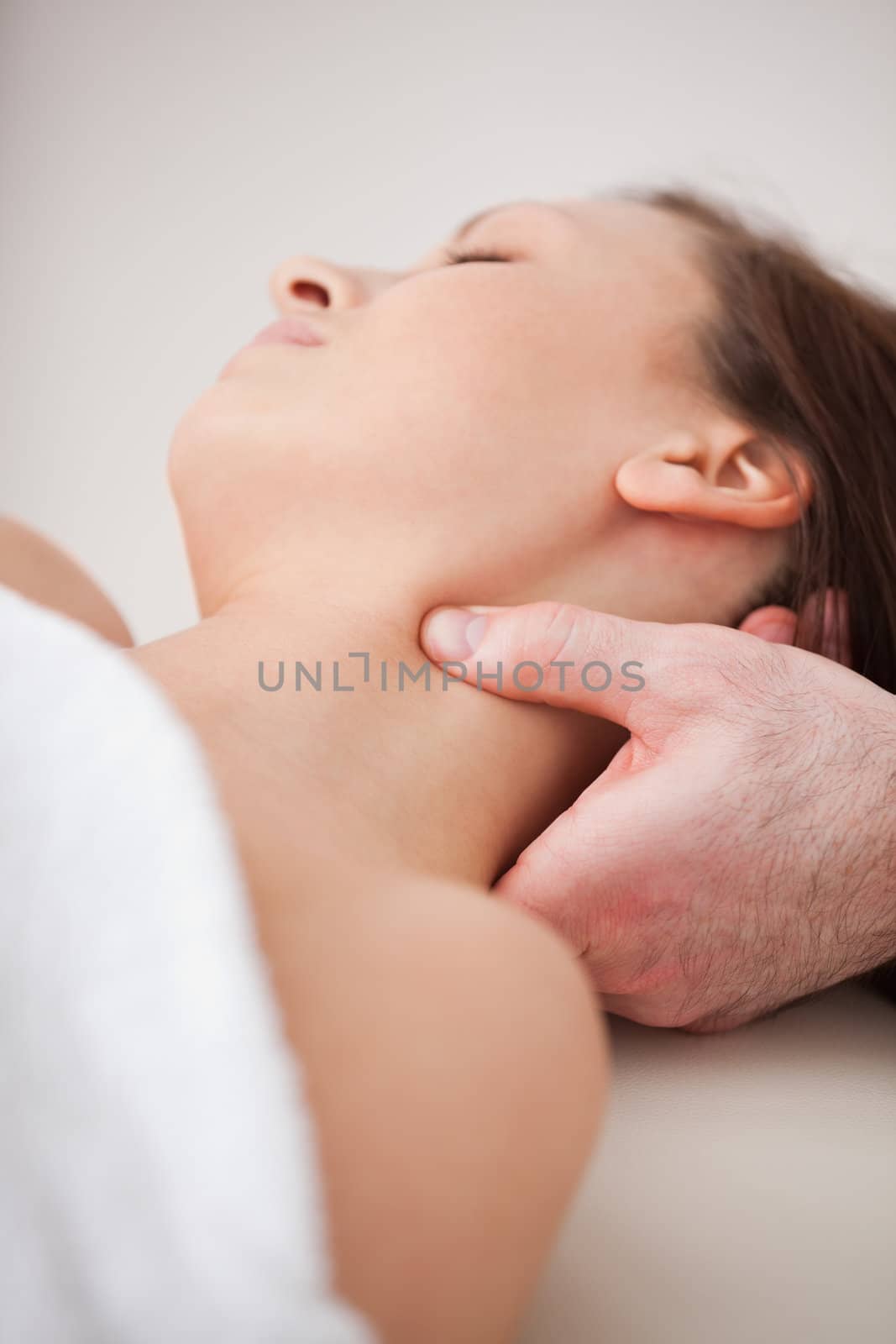 Close-up of doctor pressing his thumb on the neck of his patient indoors