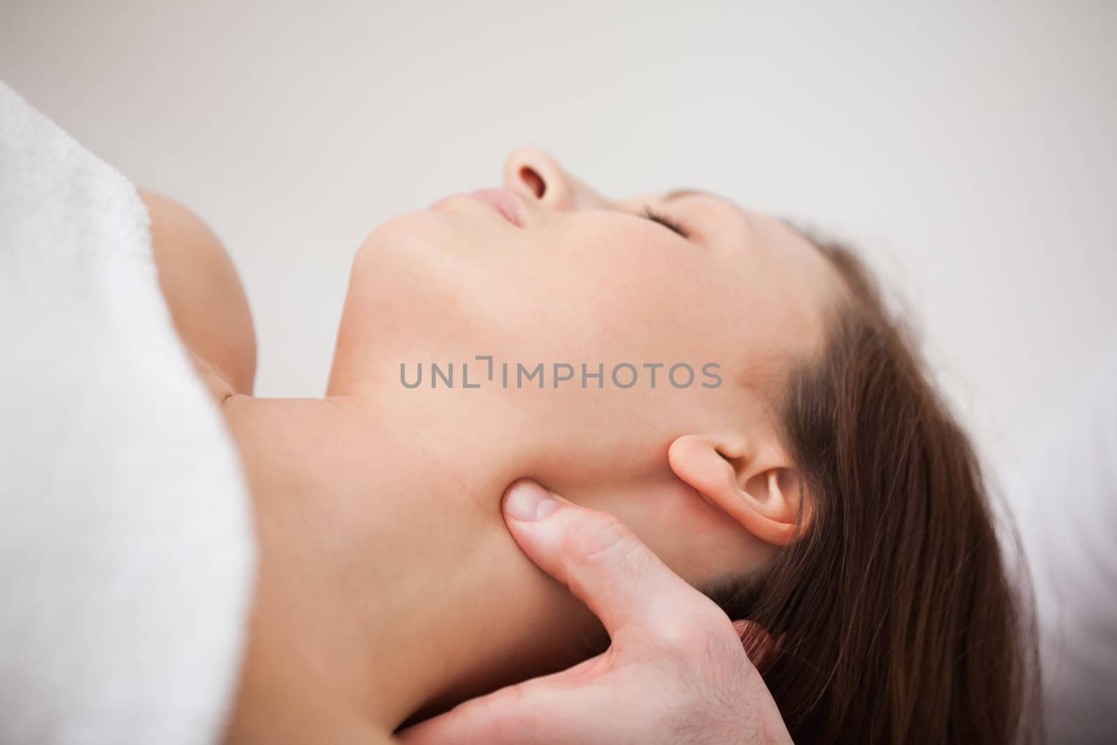 Close-up of physiotherapist pressing his thumb on the neck of a woman indoors