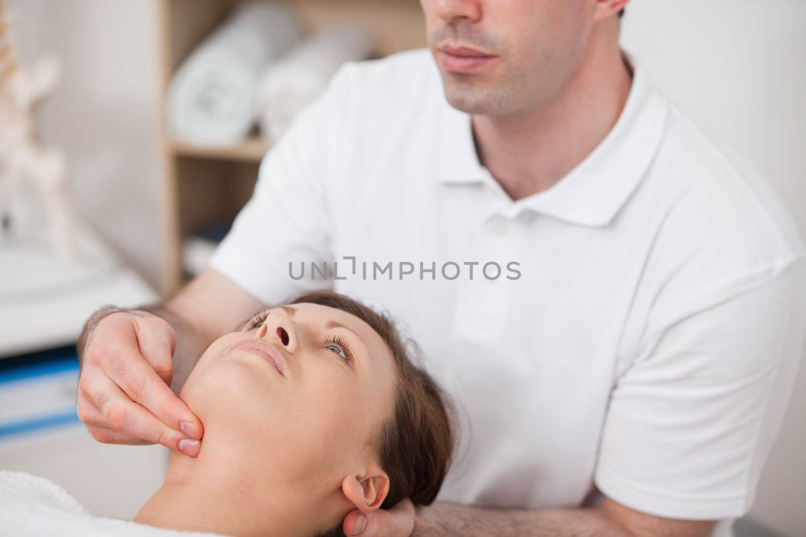 Physiotherapist pressing two fingers on the neck of his patient by Wavebreakmedia