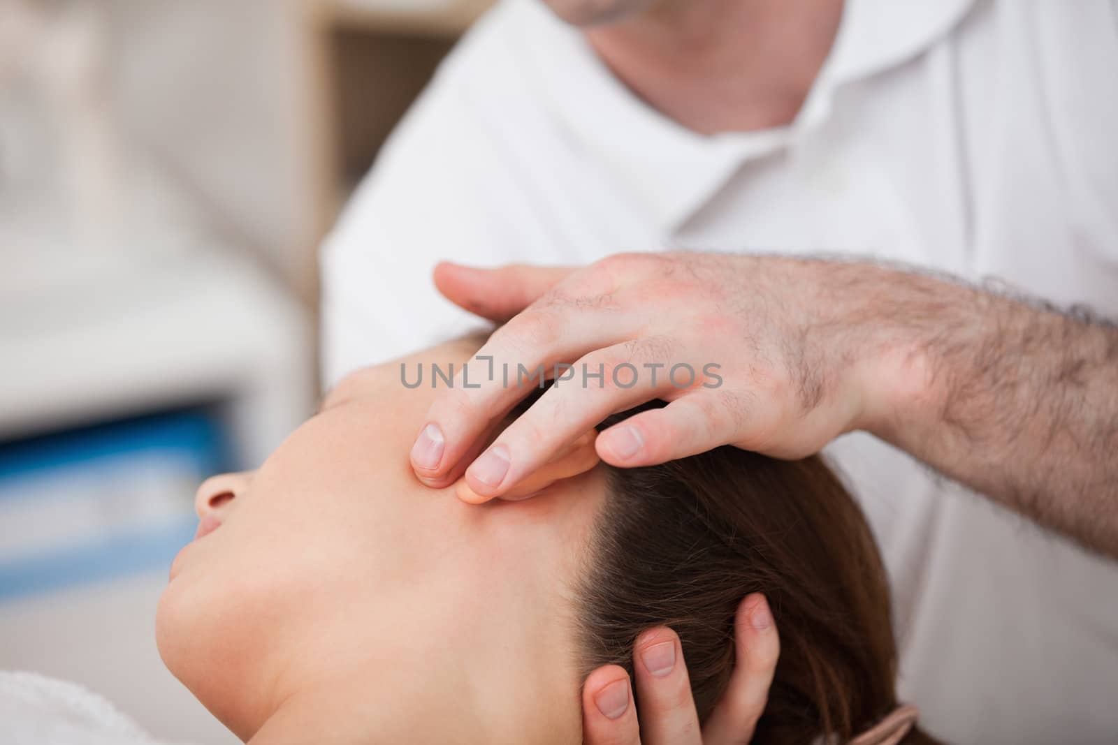 Doctor manipulating the side of the head of his patient in a room