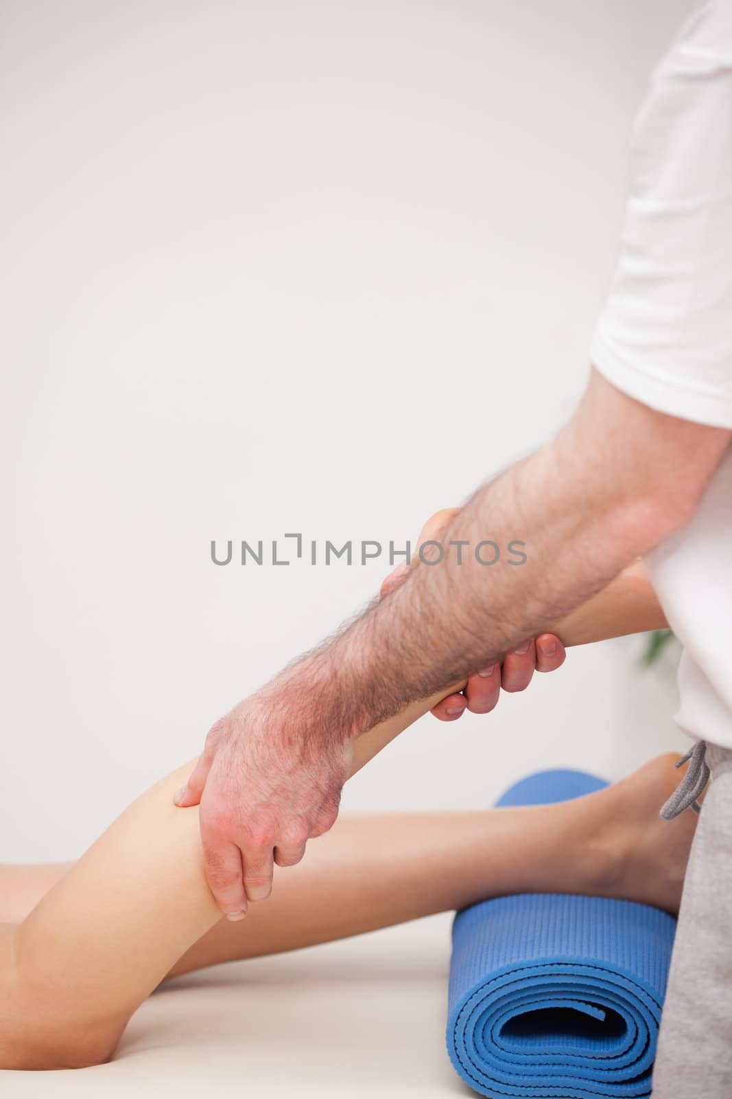 Podiatrist massaging the leg of his patient while standing in a room