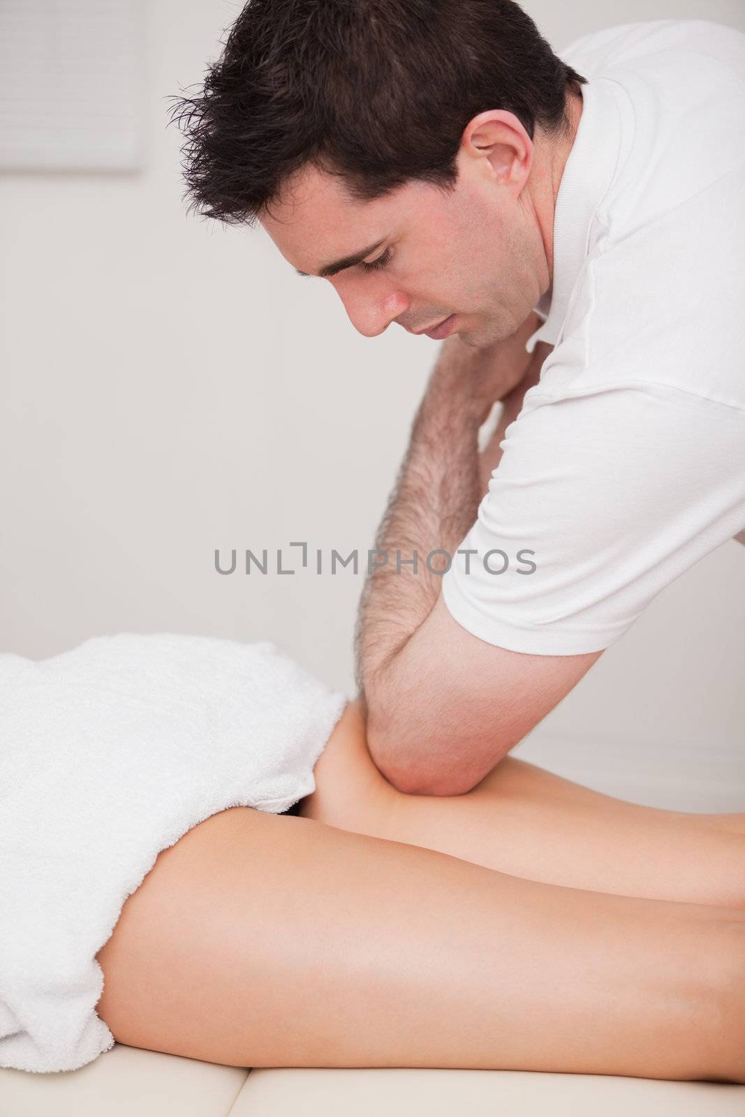 Chiropractor massaging the thigh of his patient while using his  by Wavebreakmedia
