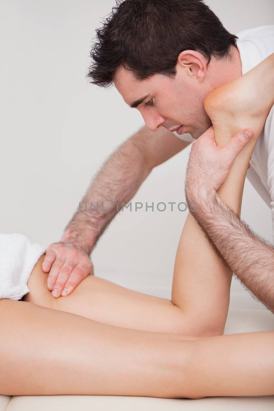 Chiropractor manipulating the leg of his patient while folding it in a room