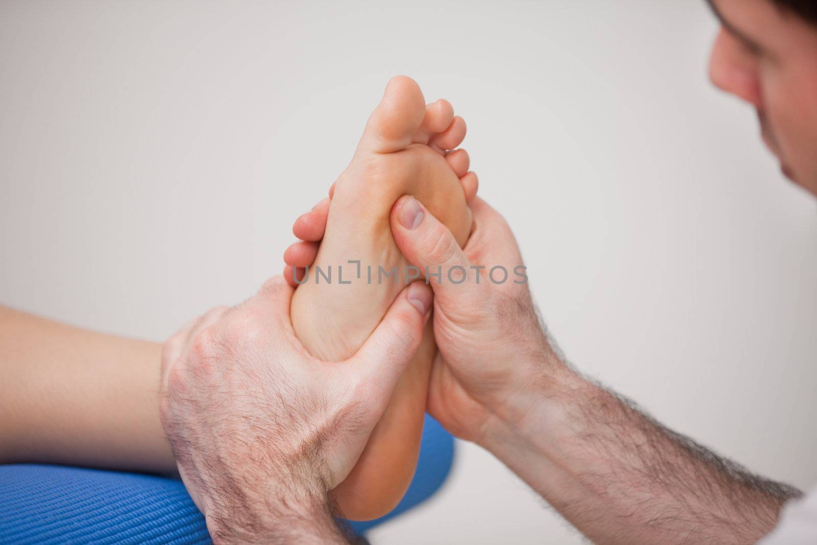 Podiatrist practicing reflexology on the foot of woman in a room