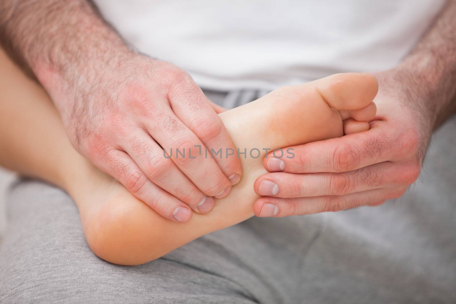 Podiatrist massaging the foot of a woman while holding it on his by Wavebreakmedia