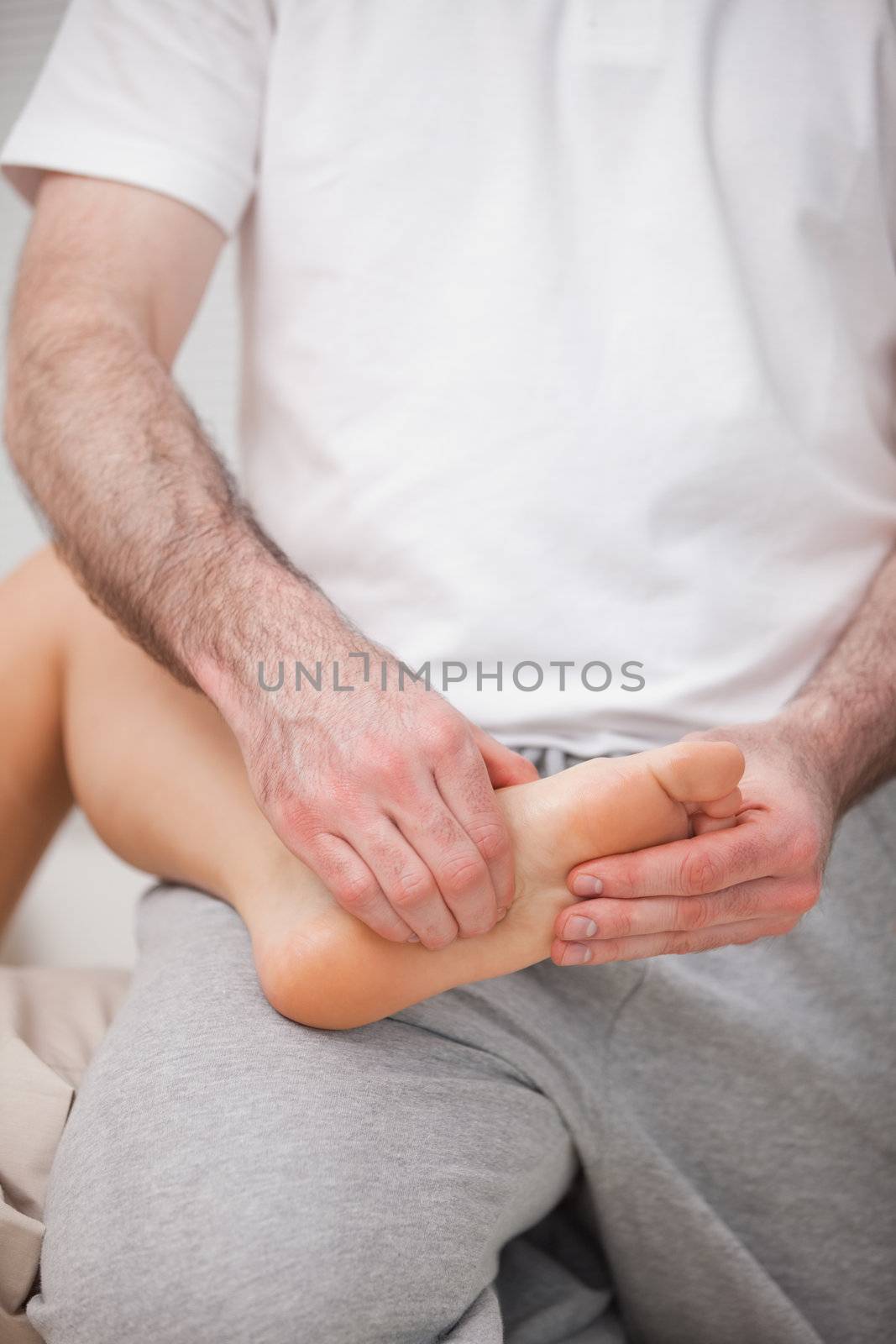 Reflexologist manipulating the sole of the patient in a room