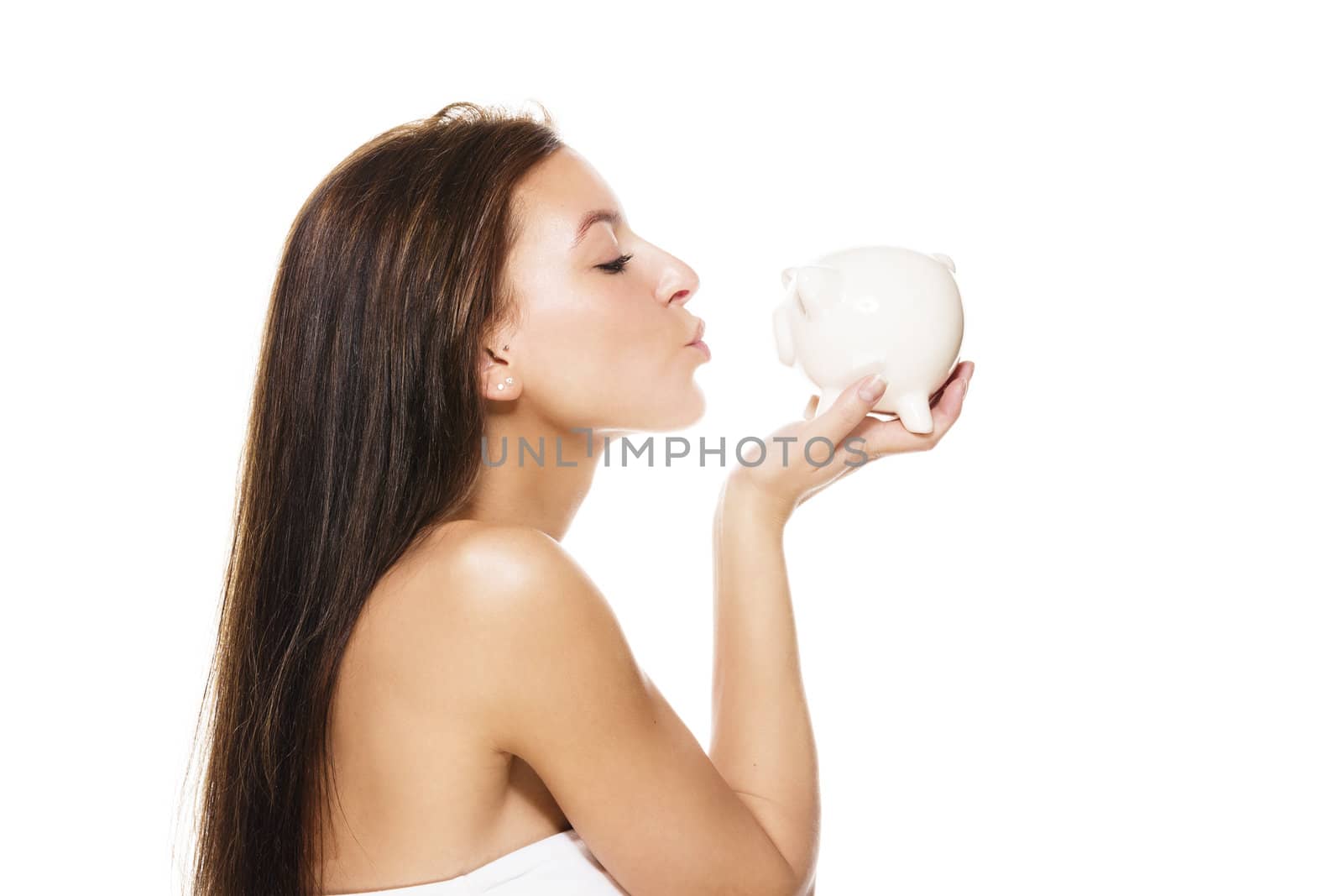 beautiful brunette woman kissing a piggy bank on white background