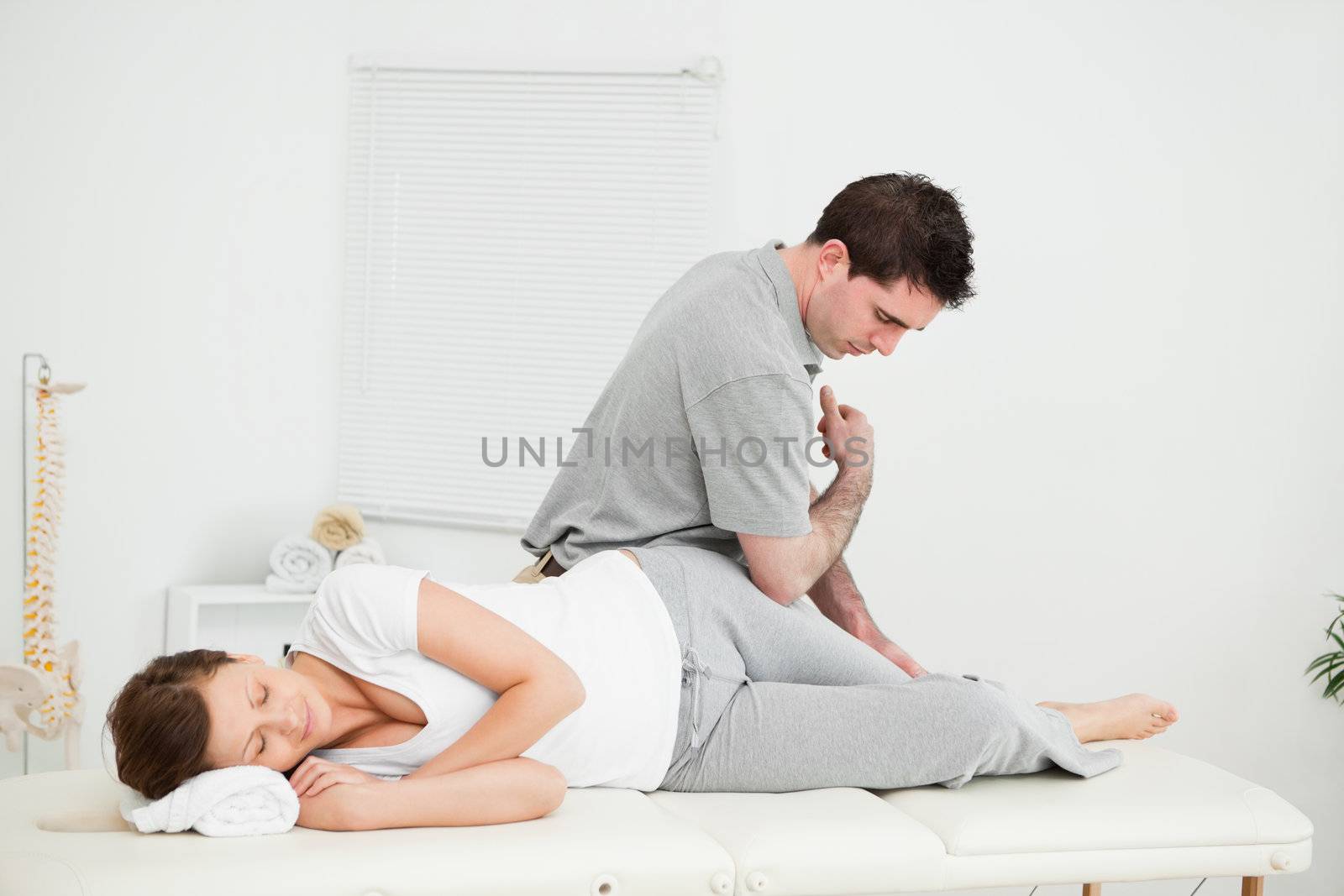 Chiropractor massaging the thigh of his patient while using his elbow in a room