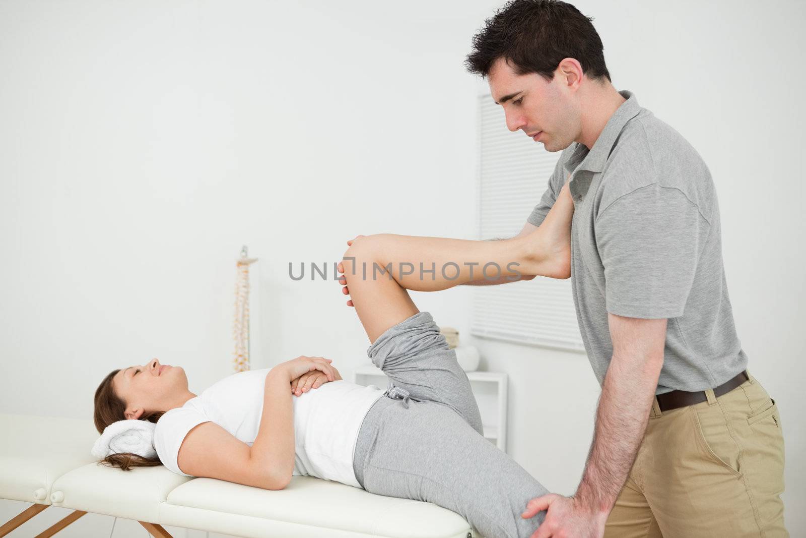 Chiropractor stretching the legs of his patient while standing in a medical room