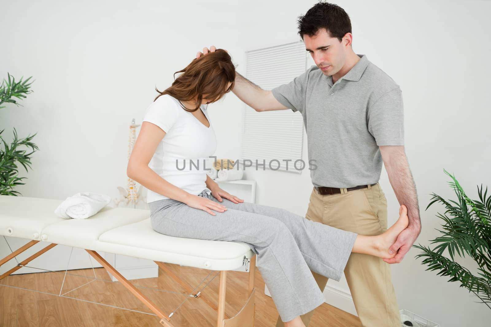 Physiotherapist manipulating his patient while standing in a medical room