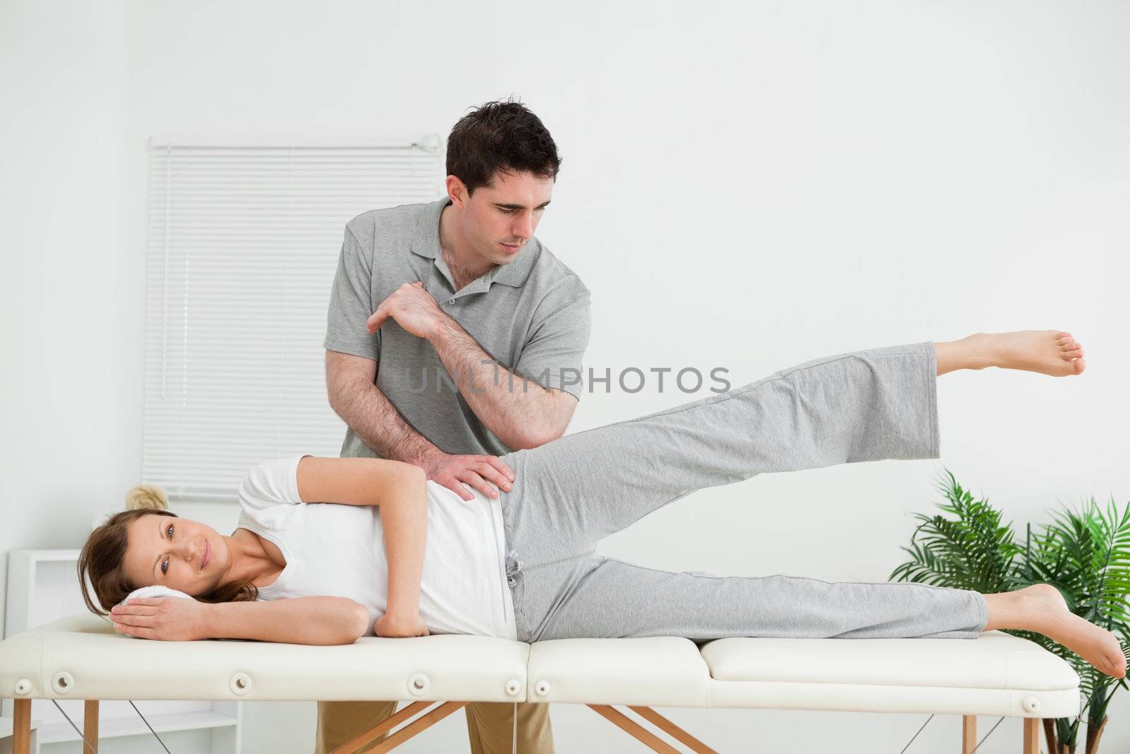 Doctor pressing his elbow on her hip while woman raising her leg by Wavebreakmedia