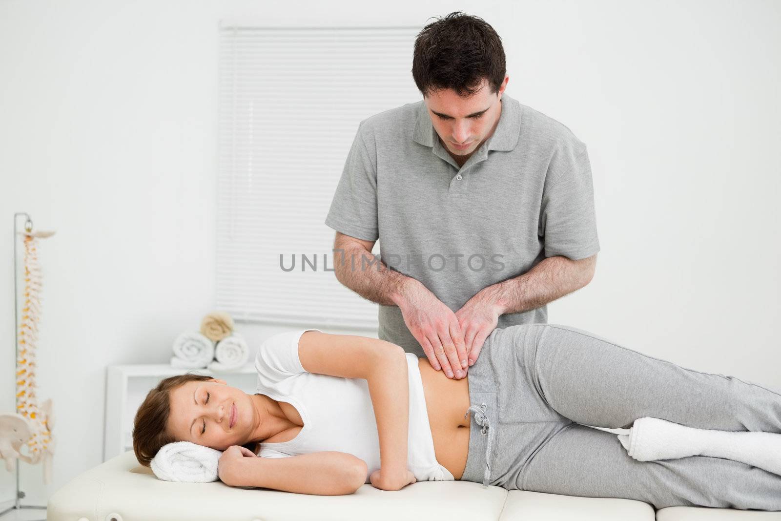 Peaceful woman being massaged on her hip by a doctor in a medical room