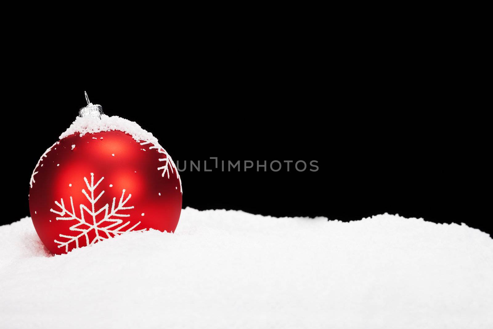 red christmas ball in snow with black background