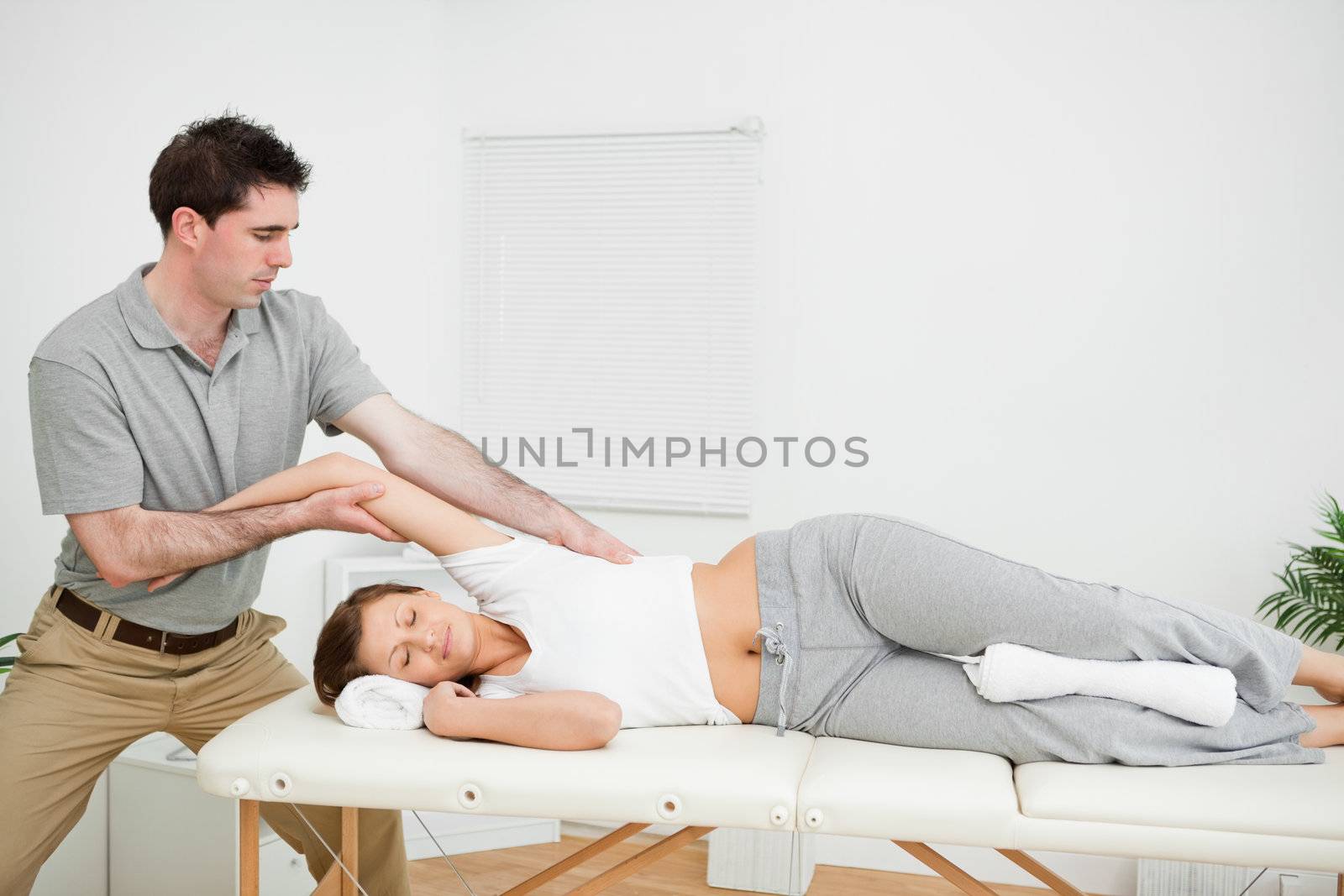 Chiropractor stretching the arm of his patient while holding it by Wavebreakmedia