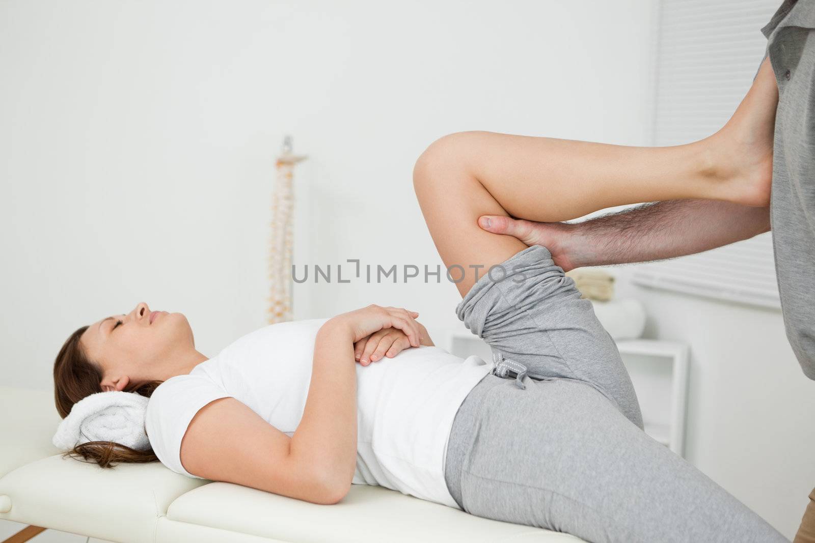 Woman putting her foot on the chest of her doctor while stretchi by Wavebreakmedia