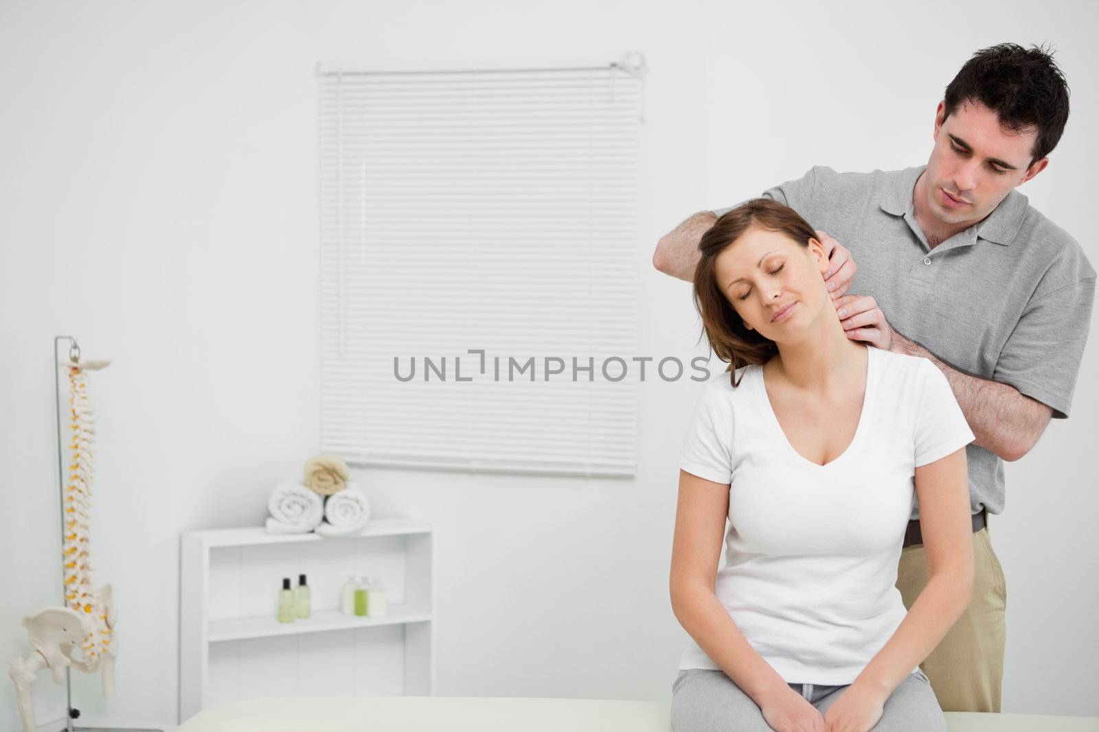 Doctor examining the neck of his patient while standing in a medical room