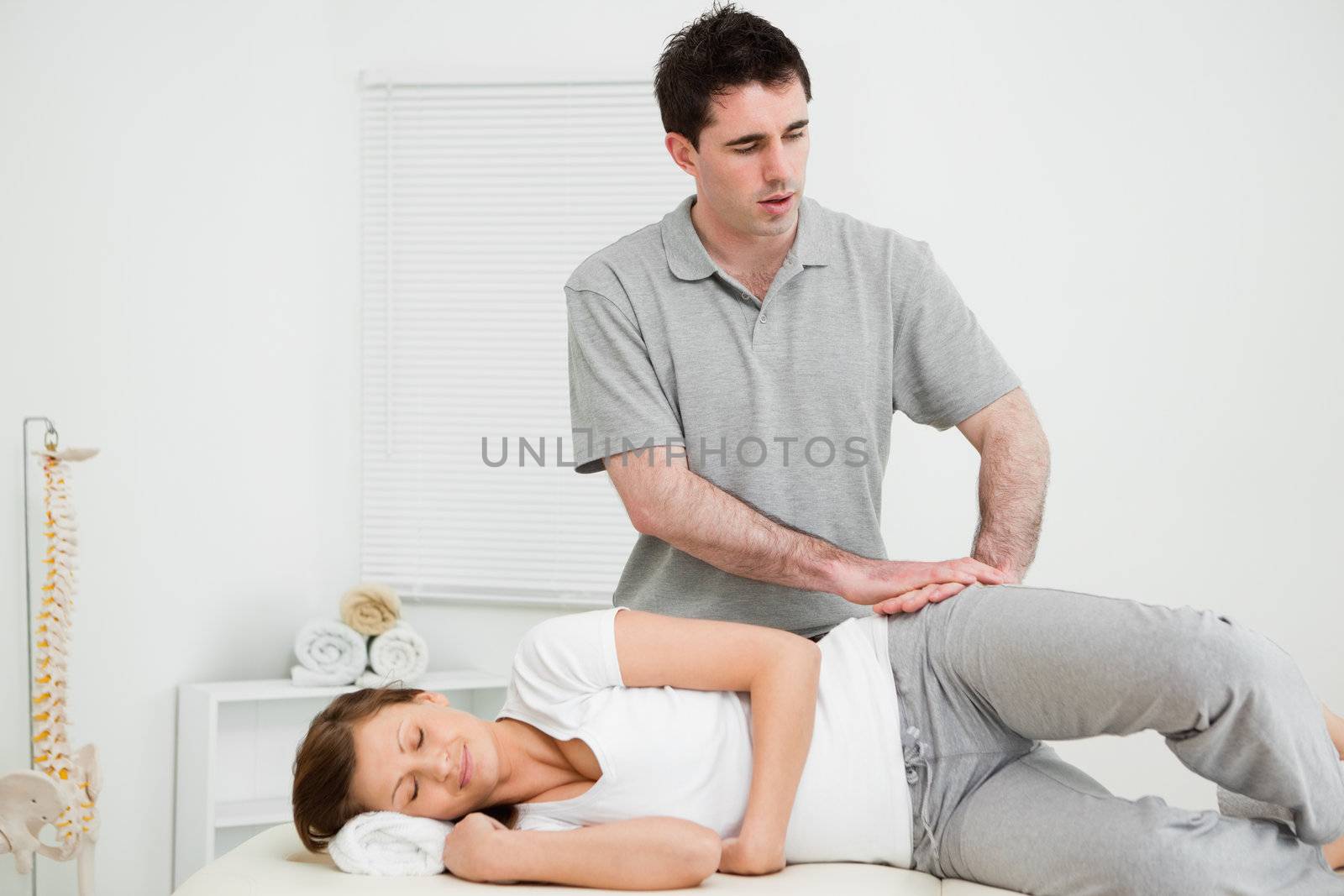 Doctor pressing his hands on the hip of his patient in a room