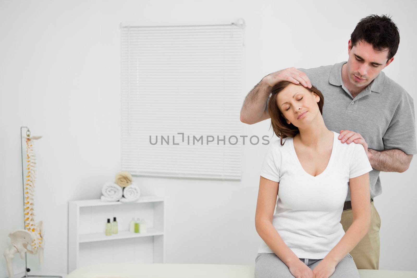 Doctor examining the neck of his patient while stretching it in a room