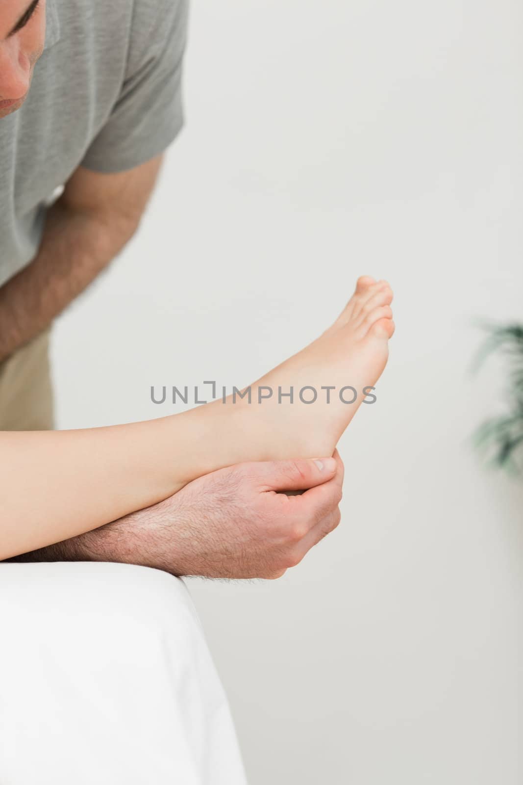 Podiatrist examining the foot of his patient in a room