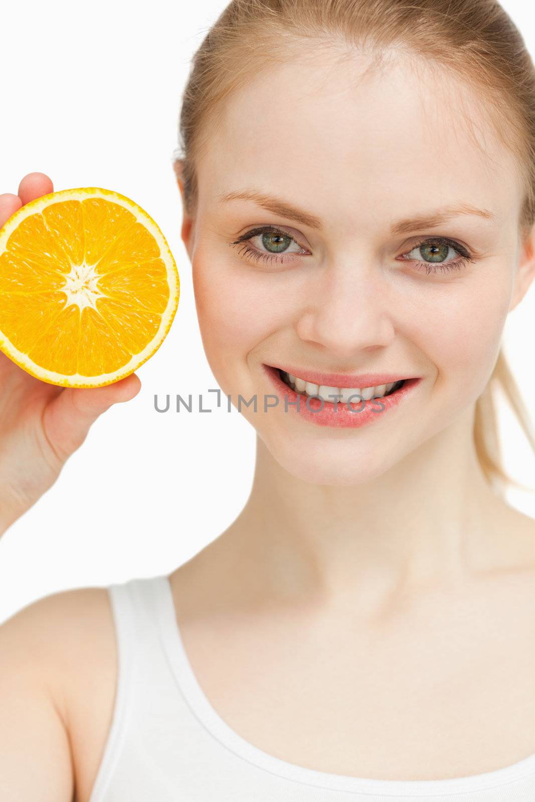 Close up of a smiling woman presenting an orange against white background
