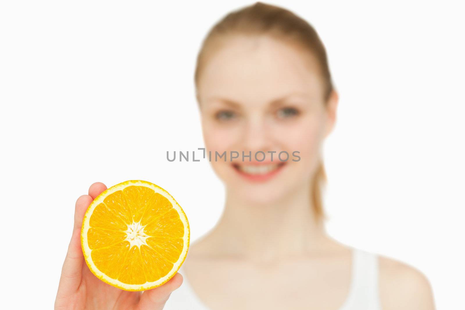 Smiling woman holding an orange against white background