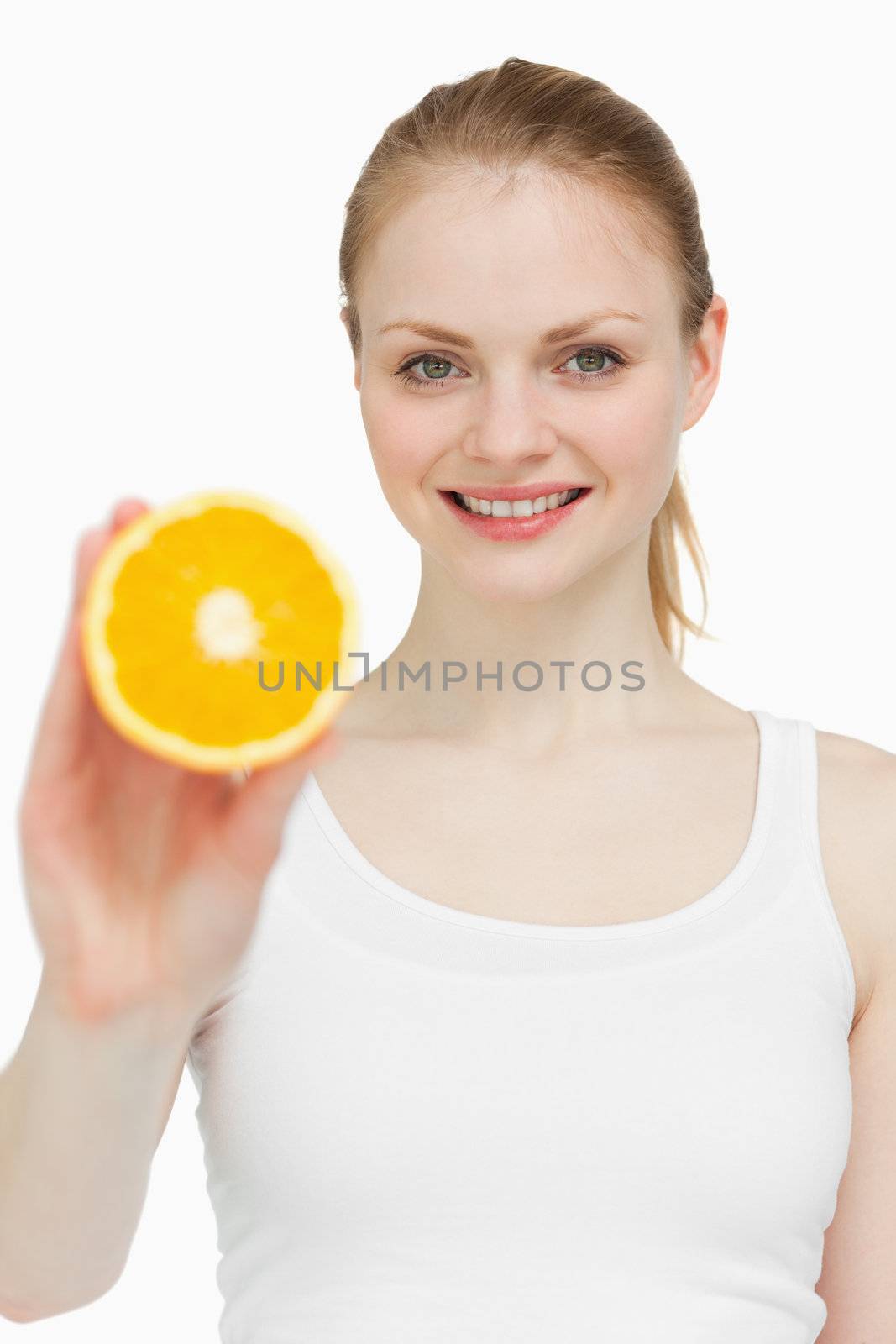 Woman holding an orange while smiling against white background