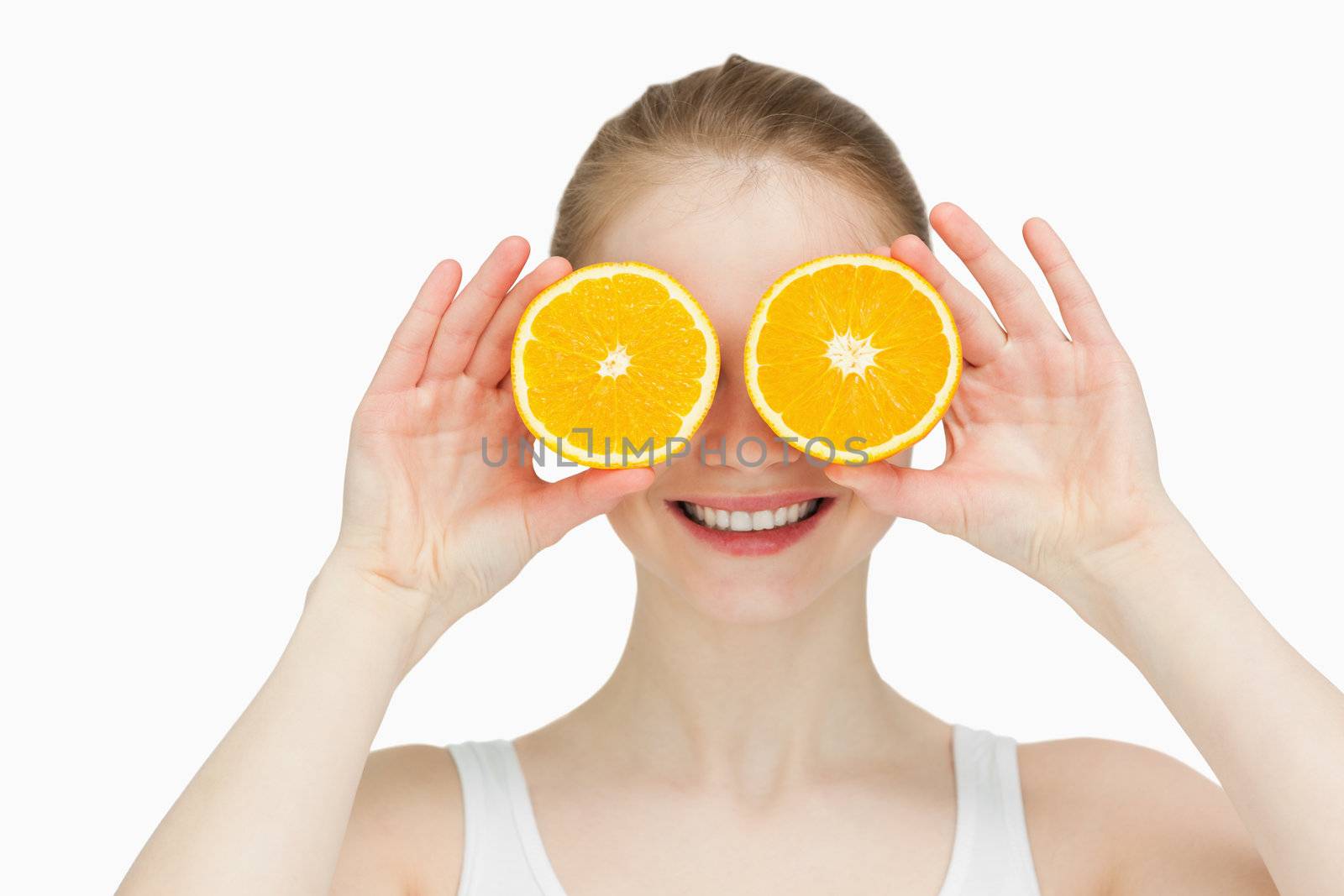 Smiling woman placing oranges on her eyes by Wavebreakmedia