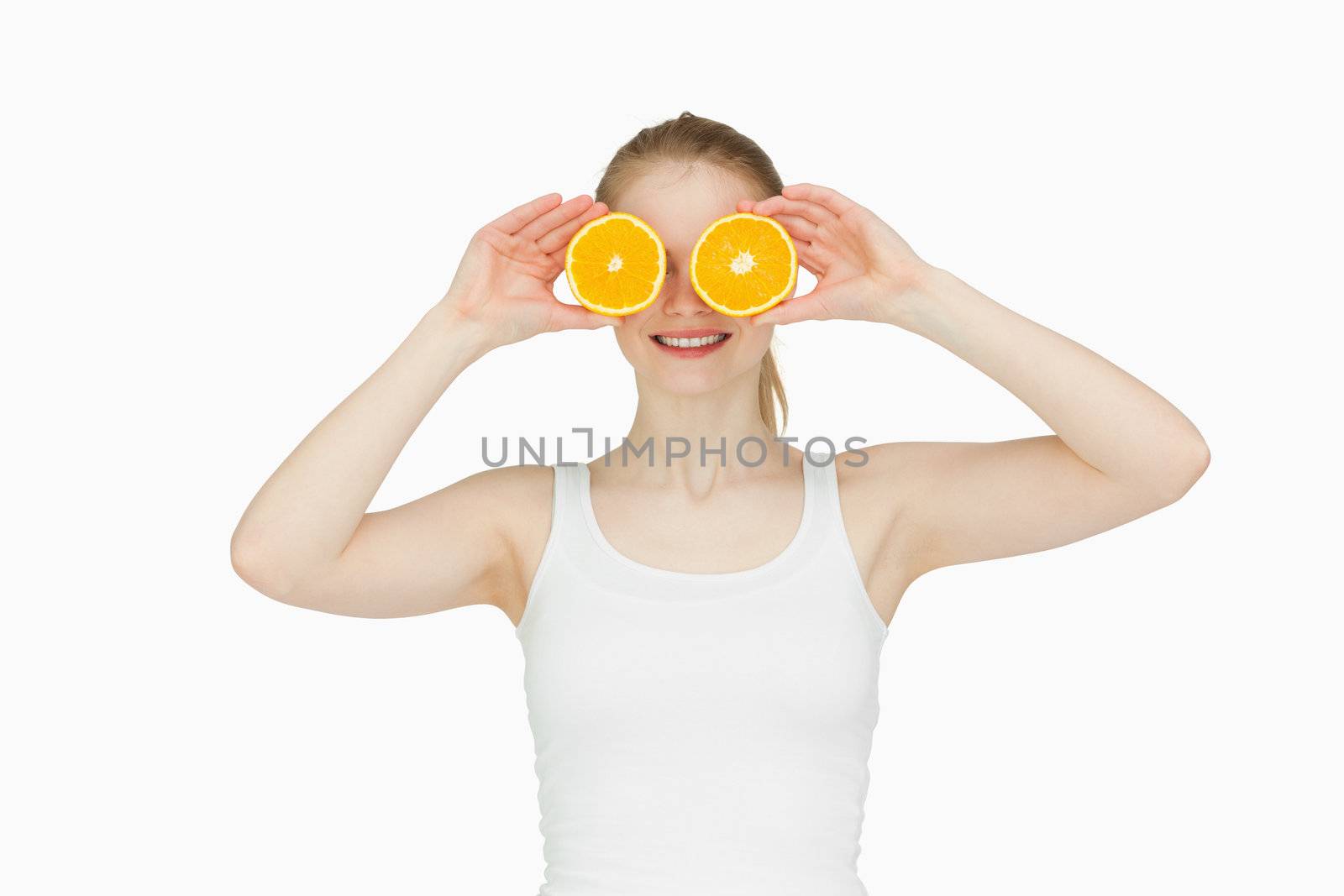 Blond-haired woman placing oranges on her eyes against white background