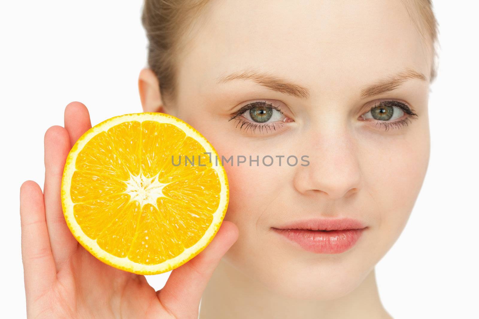 Close up of a woman presenting an orange against white background