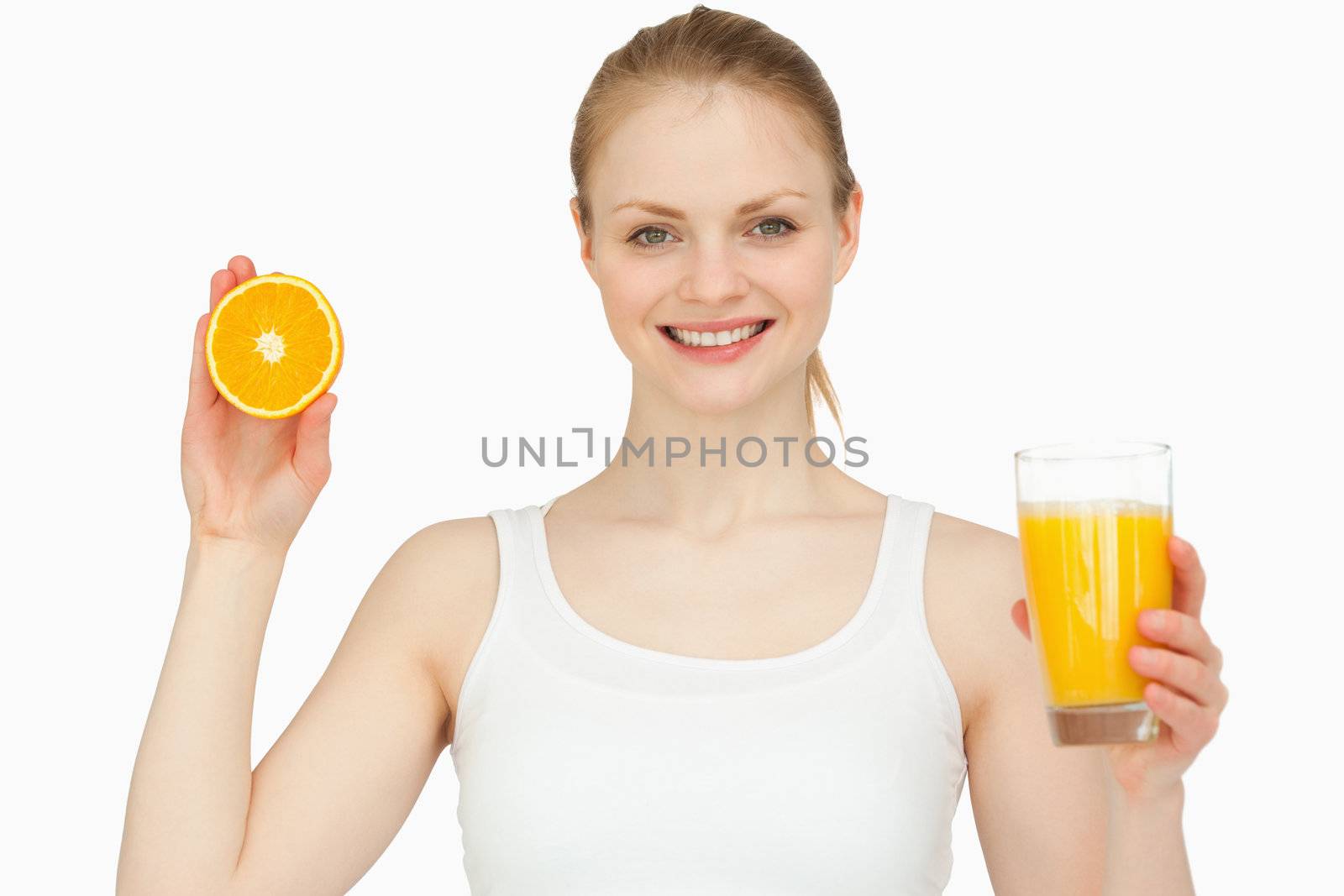Woman holding a glass while presenting an orange against white background