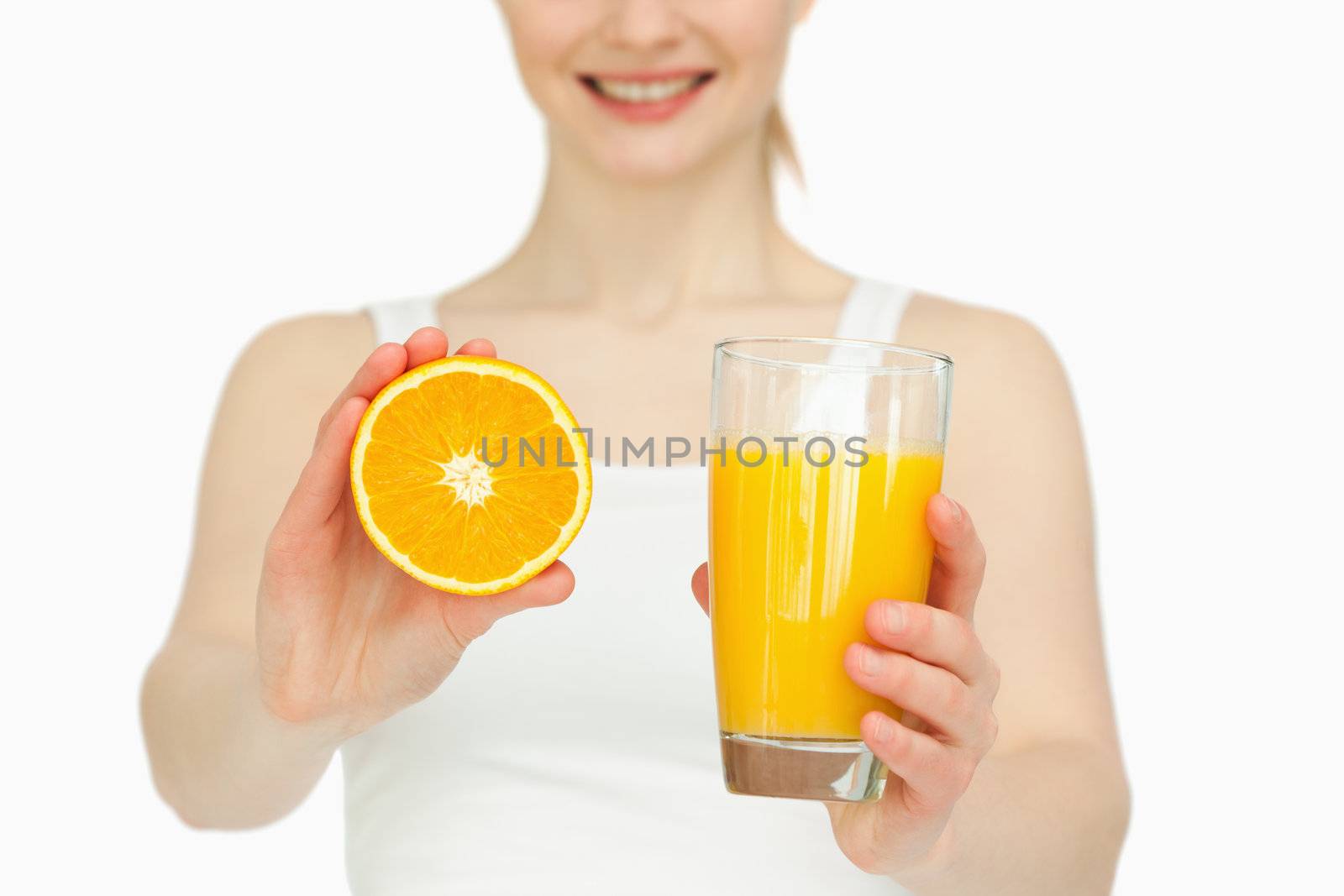Woman presenting an orange while holding a glass against white background