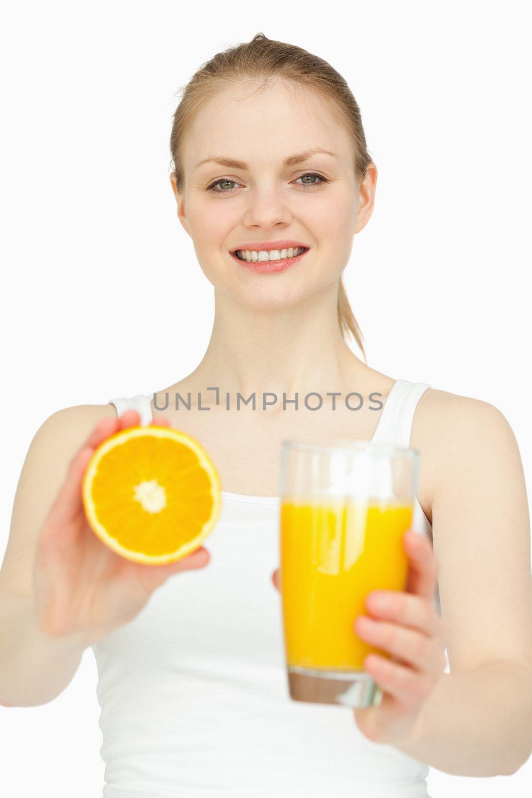 Smiling woman holding a glass while presenting an orange against white background