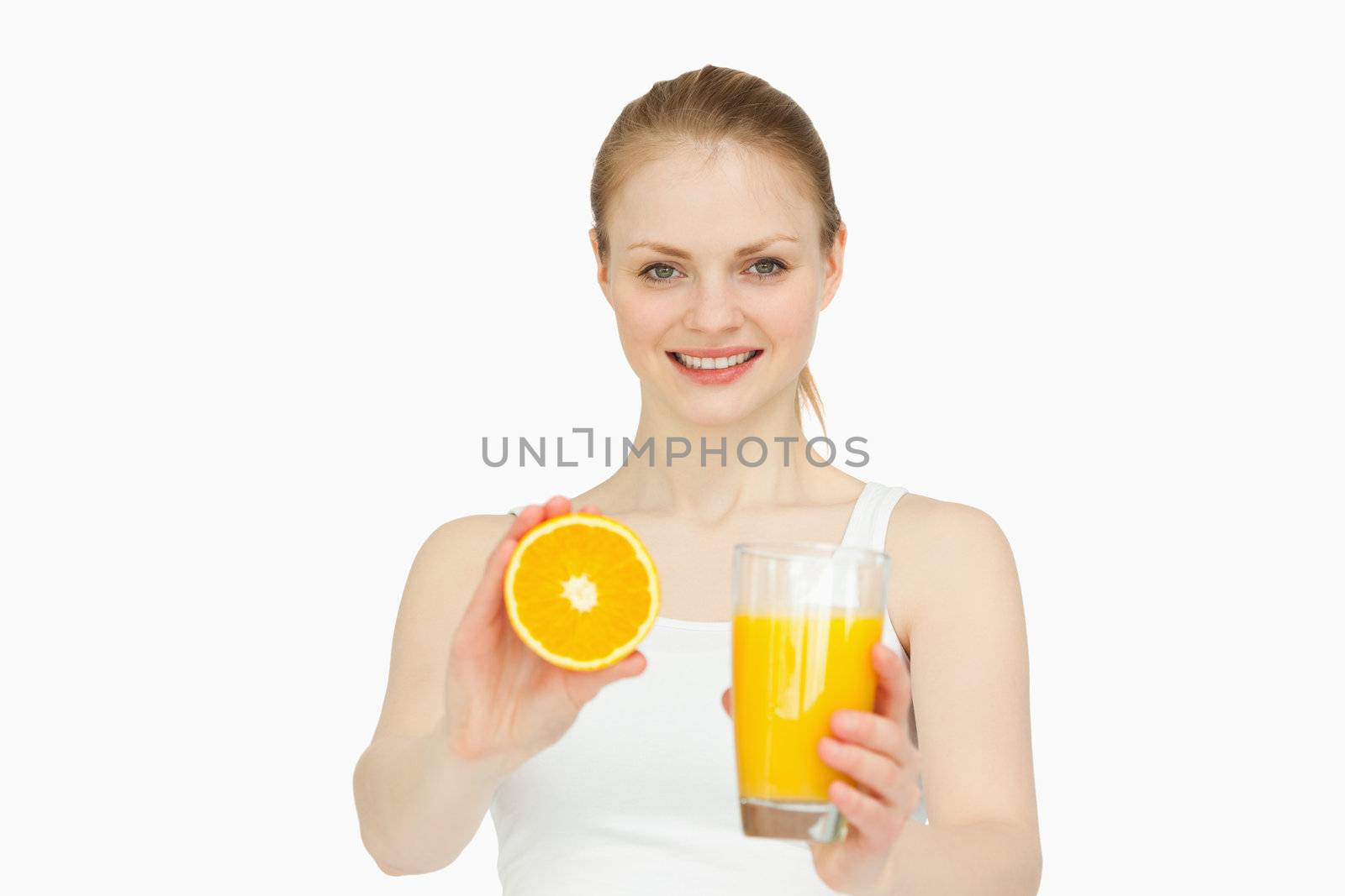 Cheerful woman presenting an orange while holding a glass by Wavebreakmedia