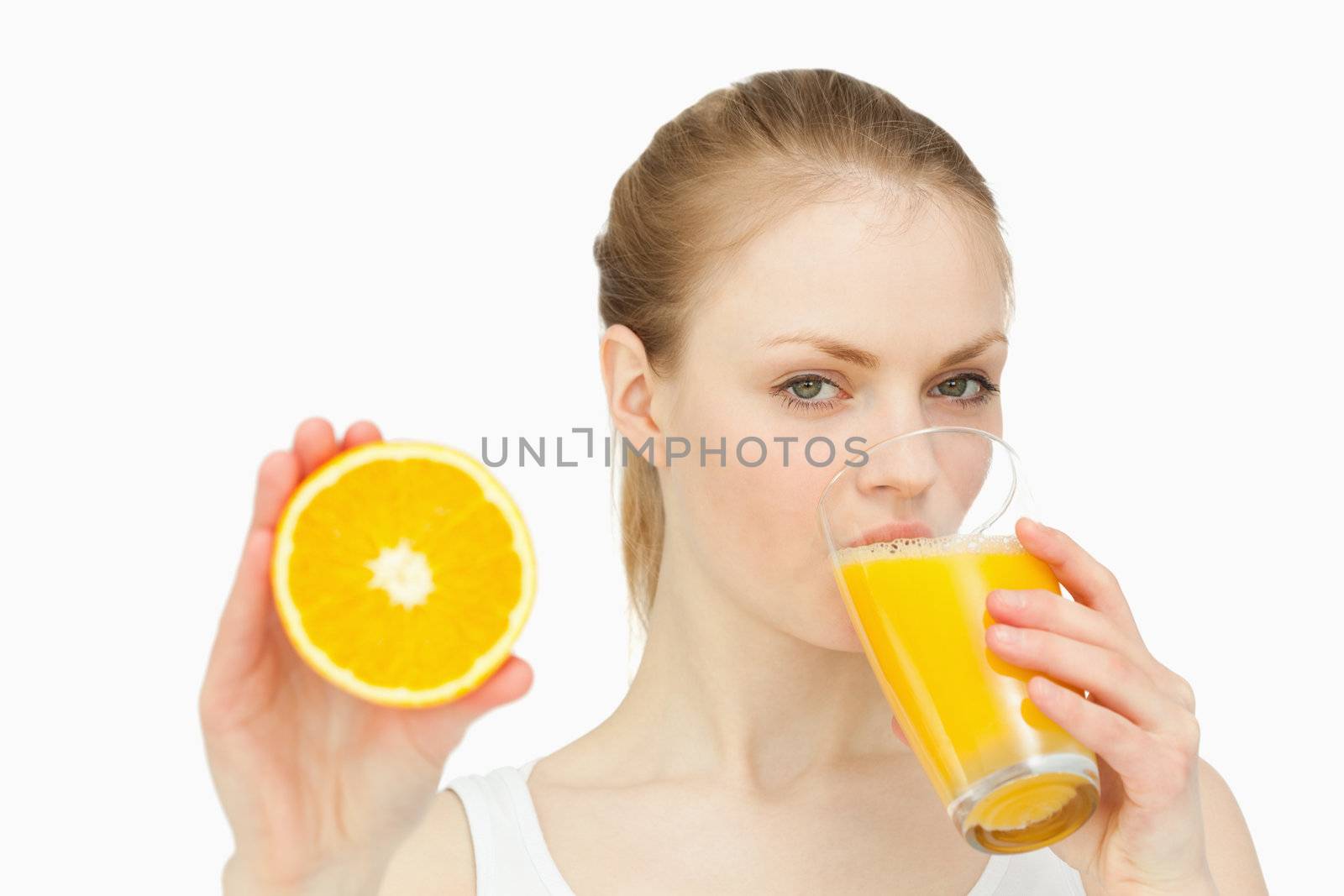 Woman presenting an orange while drinking by Wavebreakmedia