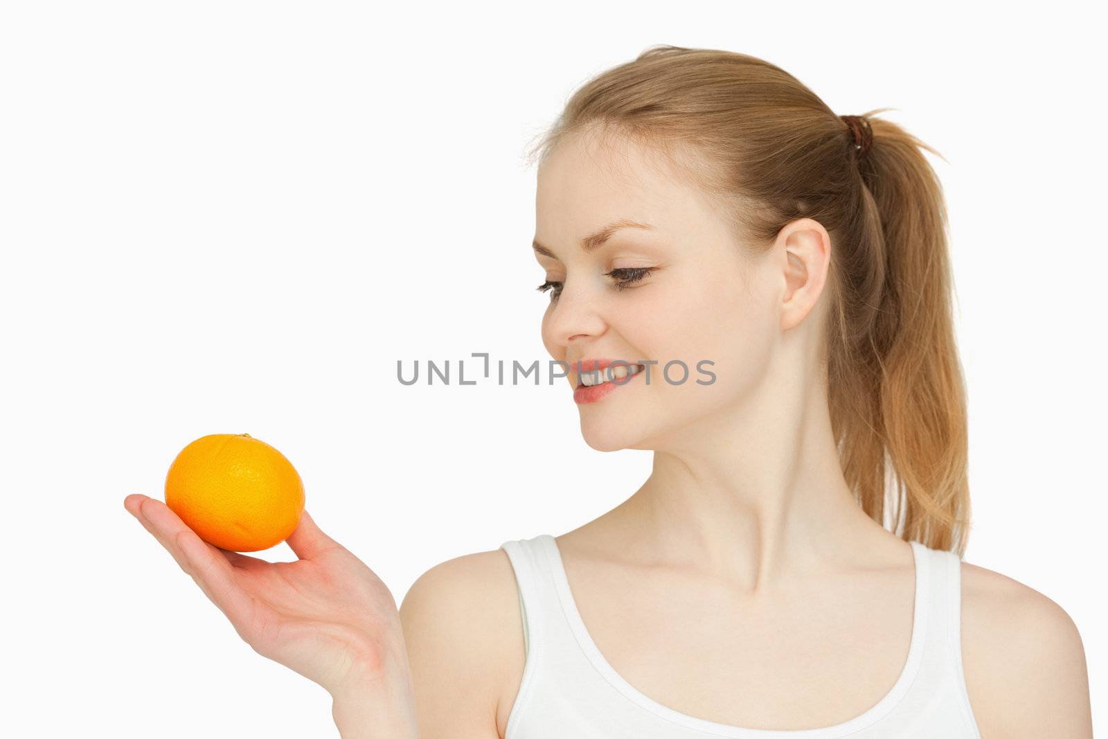 Woman holding a tangerine while looking at it against white background