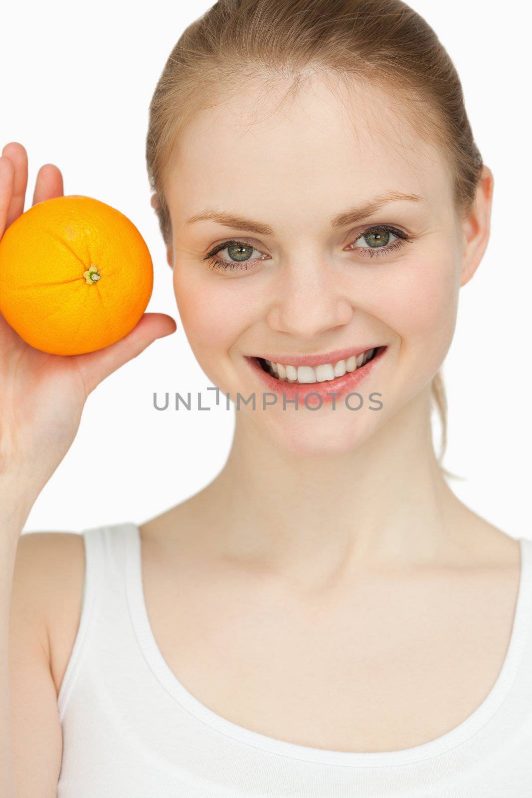 Smiling blonde-haired presenting an orange against white background