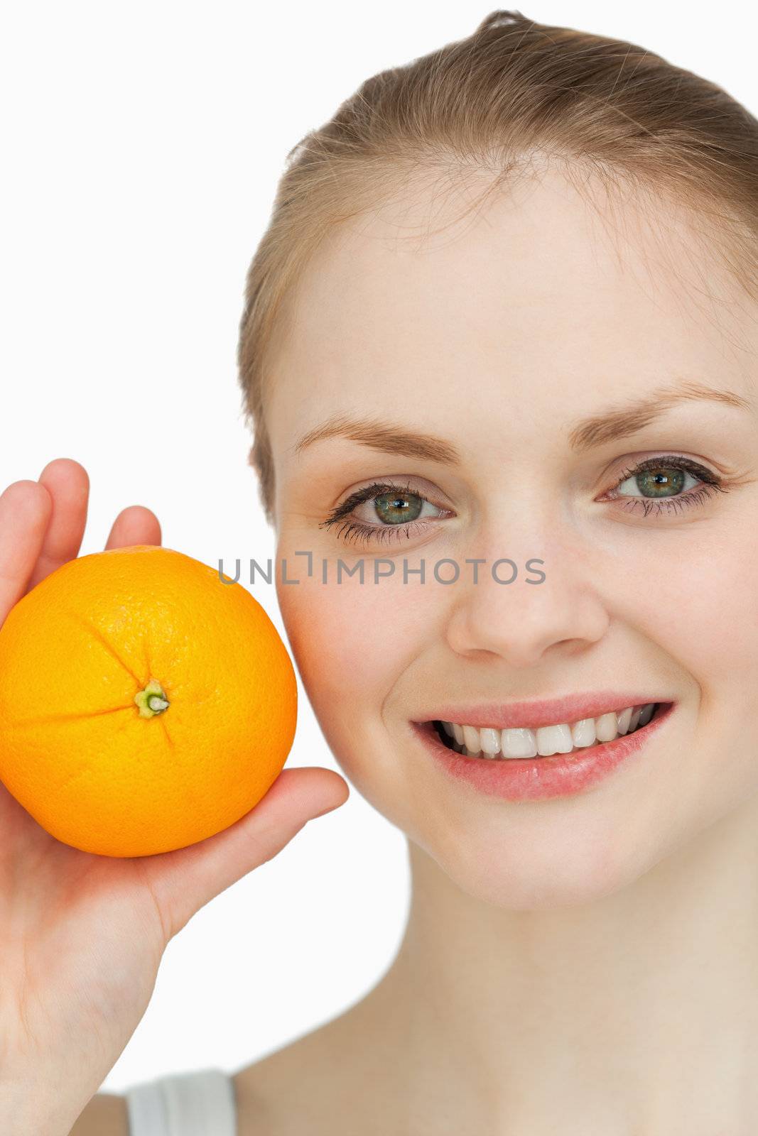 Fair-haired woman presenting an orange against white background