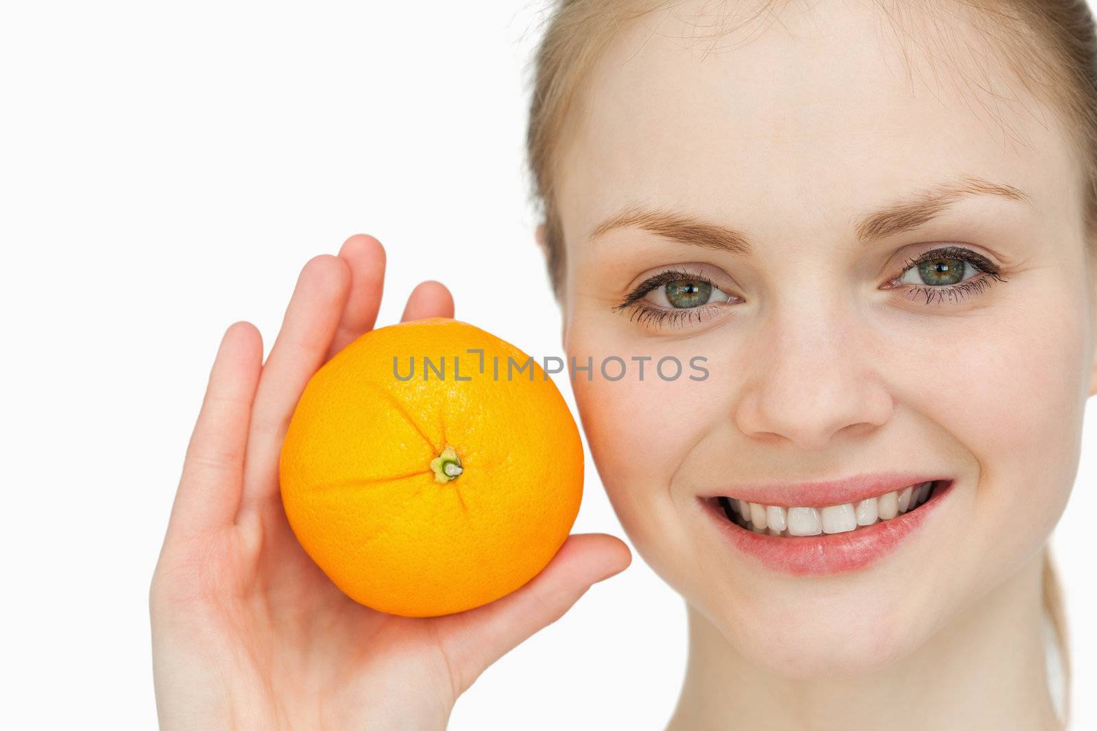 fair-haired woman holding an orange against white background
