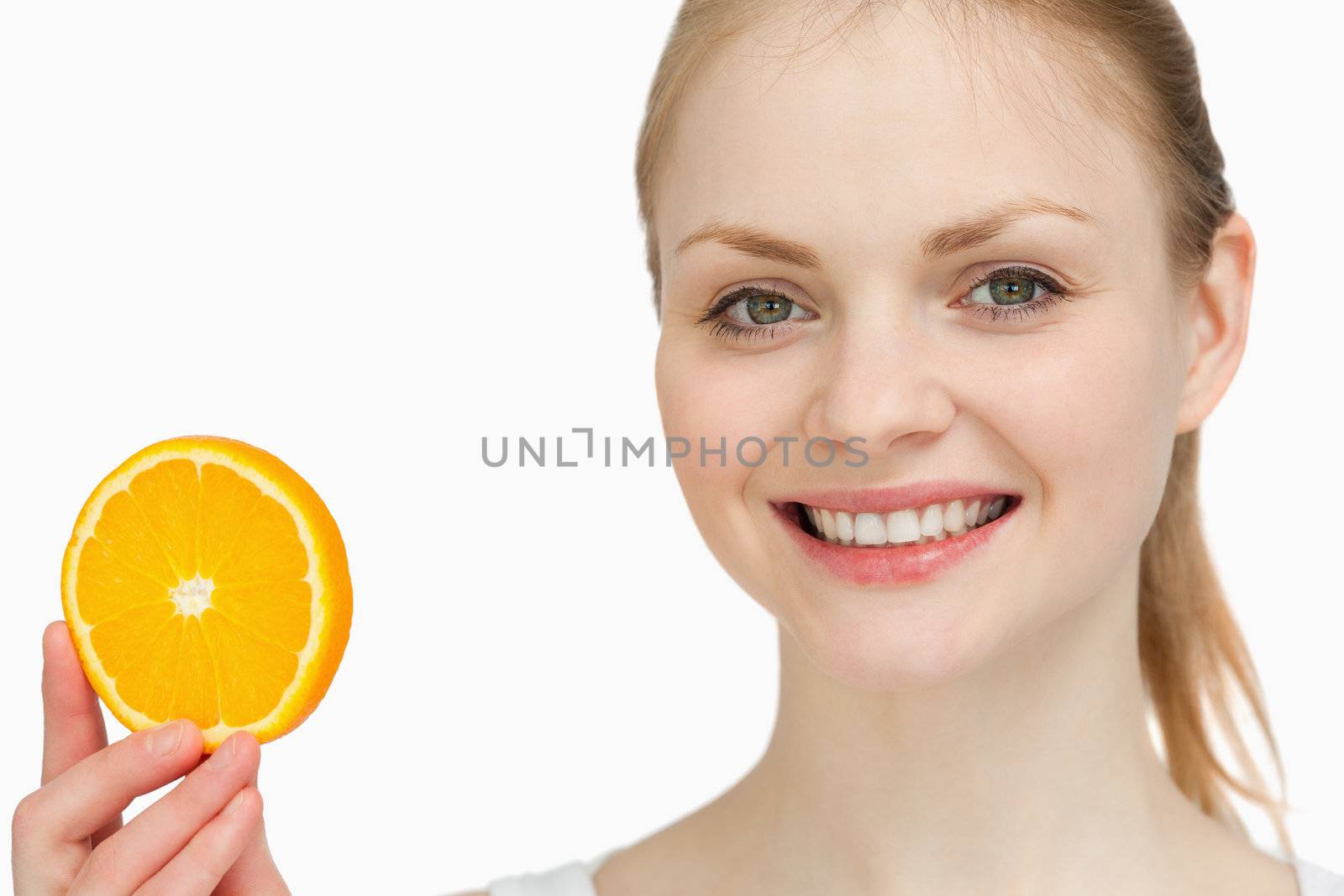 Smiling woman presenting an orange slice against white background