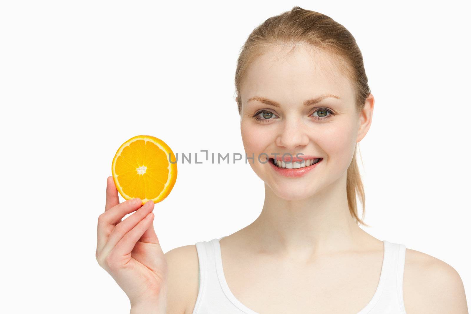 Cheerful woman presenting an orange slice against white background