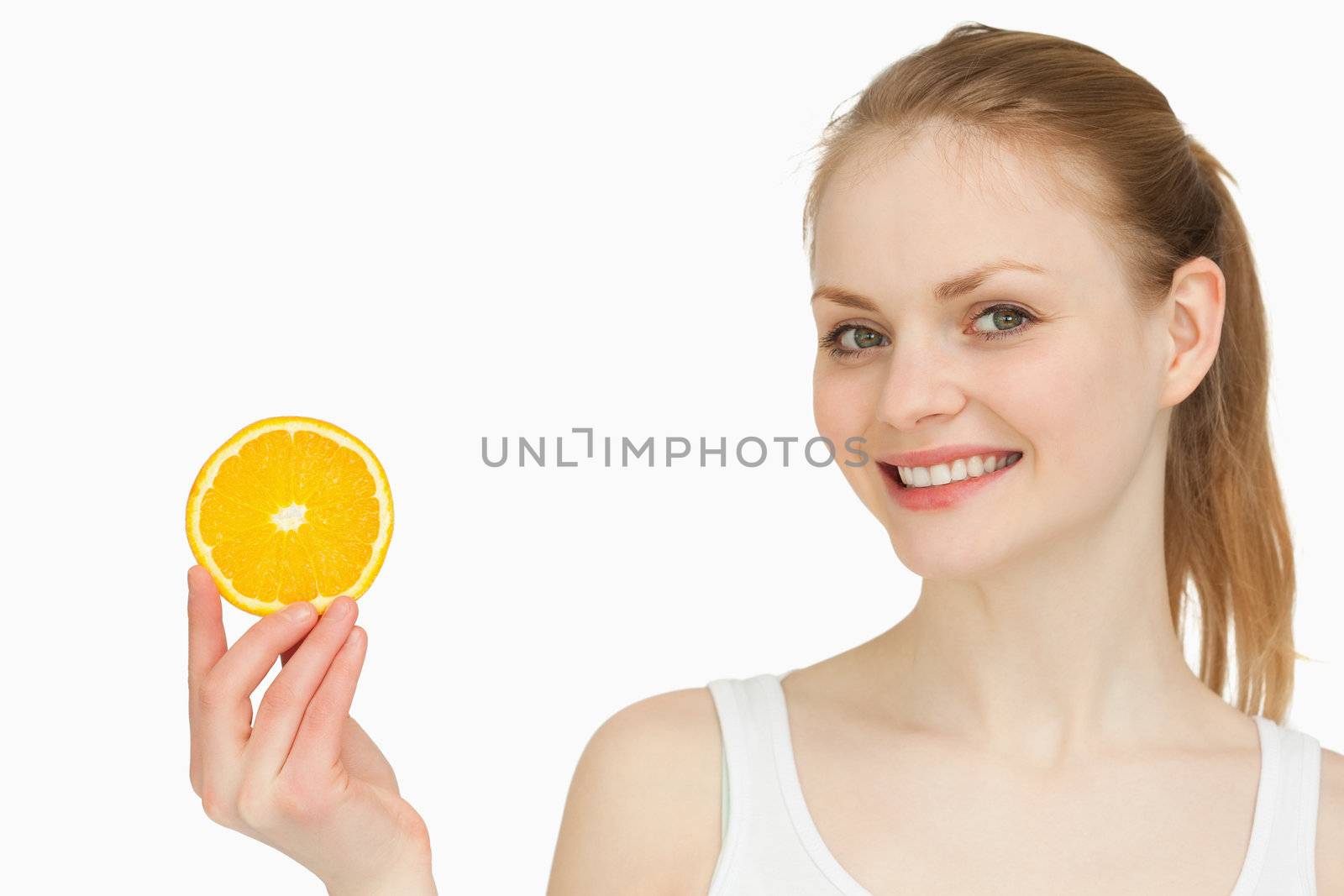 Cheerful woman holding an orange slice against white background