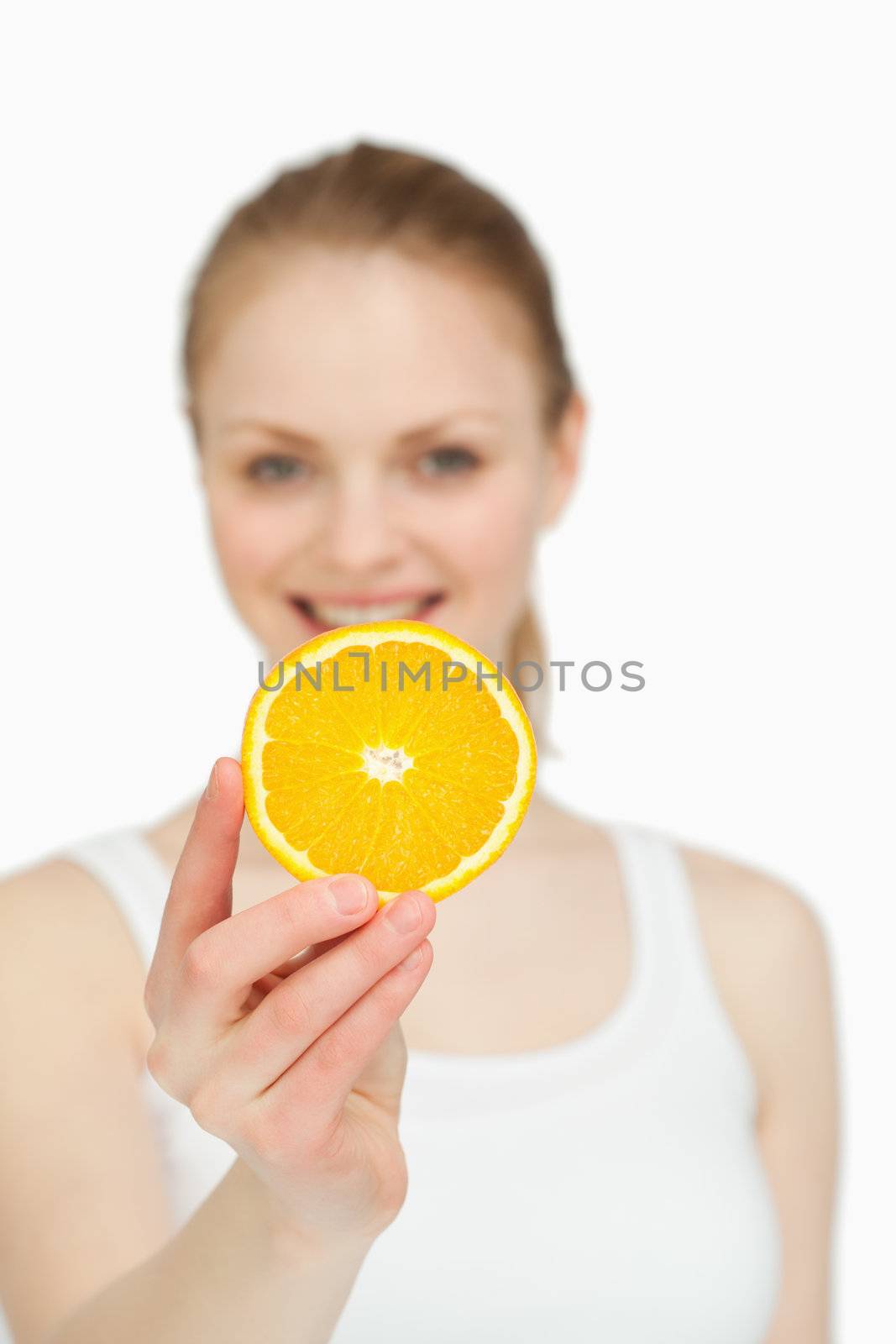 Woman presenting an orange slice while smiling against white background